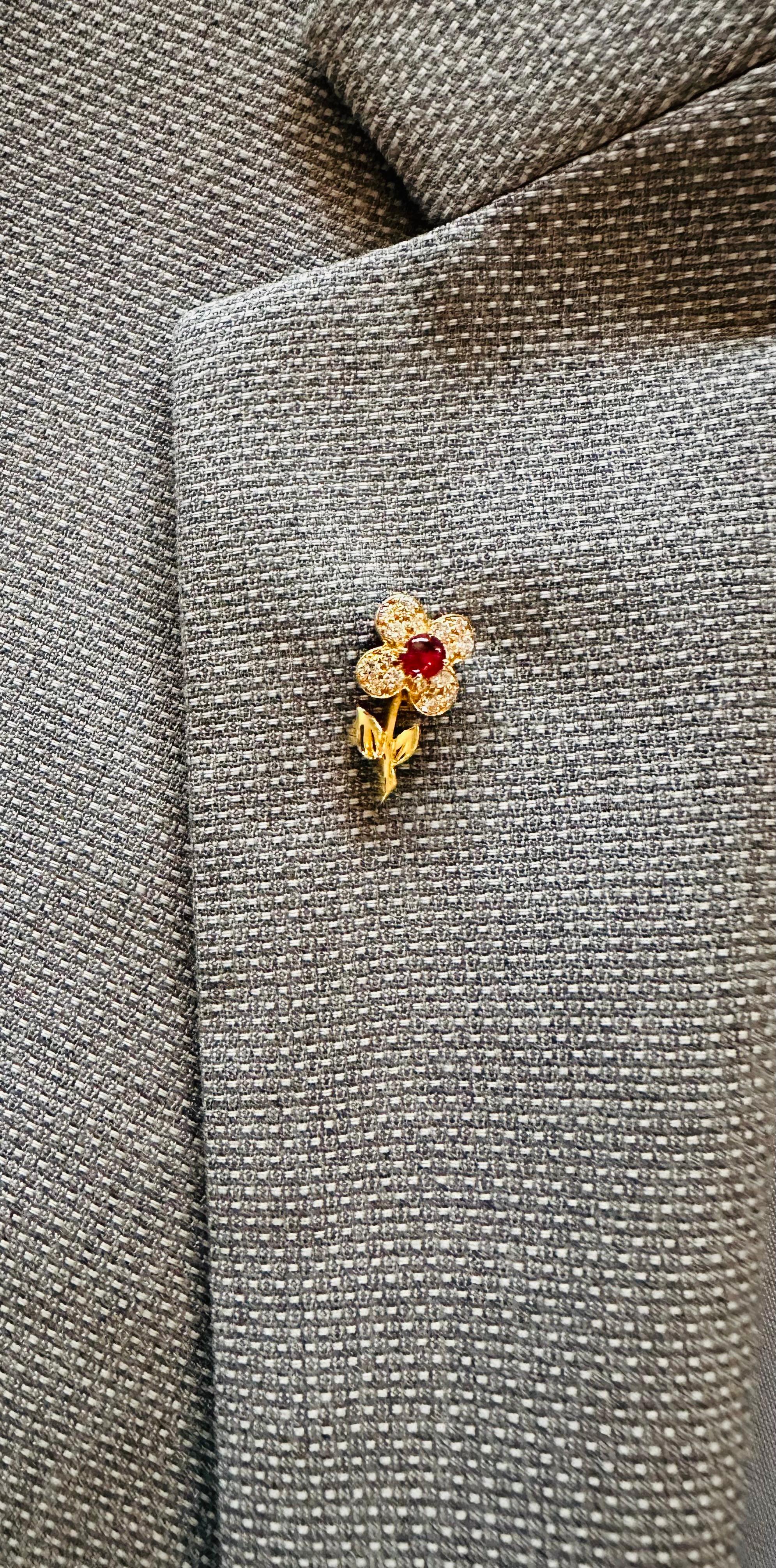 Van Cleef & Arpels Lapel Pin
Cabochon Cut Red Ruby Est .50 cts  
16 Brilliant Cut Diamonds .50 cts
Cute little flower pen 20 x 10 mm. 
Hallmarked VCA
French Eagles head
Workshop marks
Numbered B1 2066–12. Circa 2015