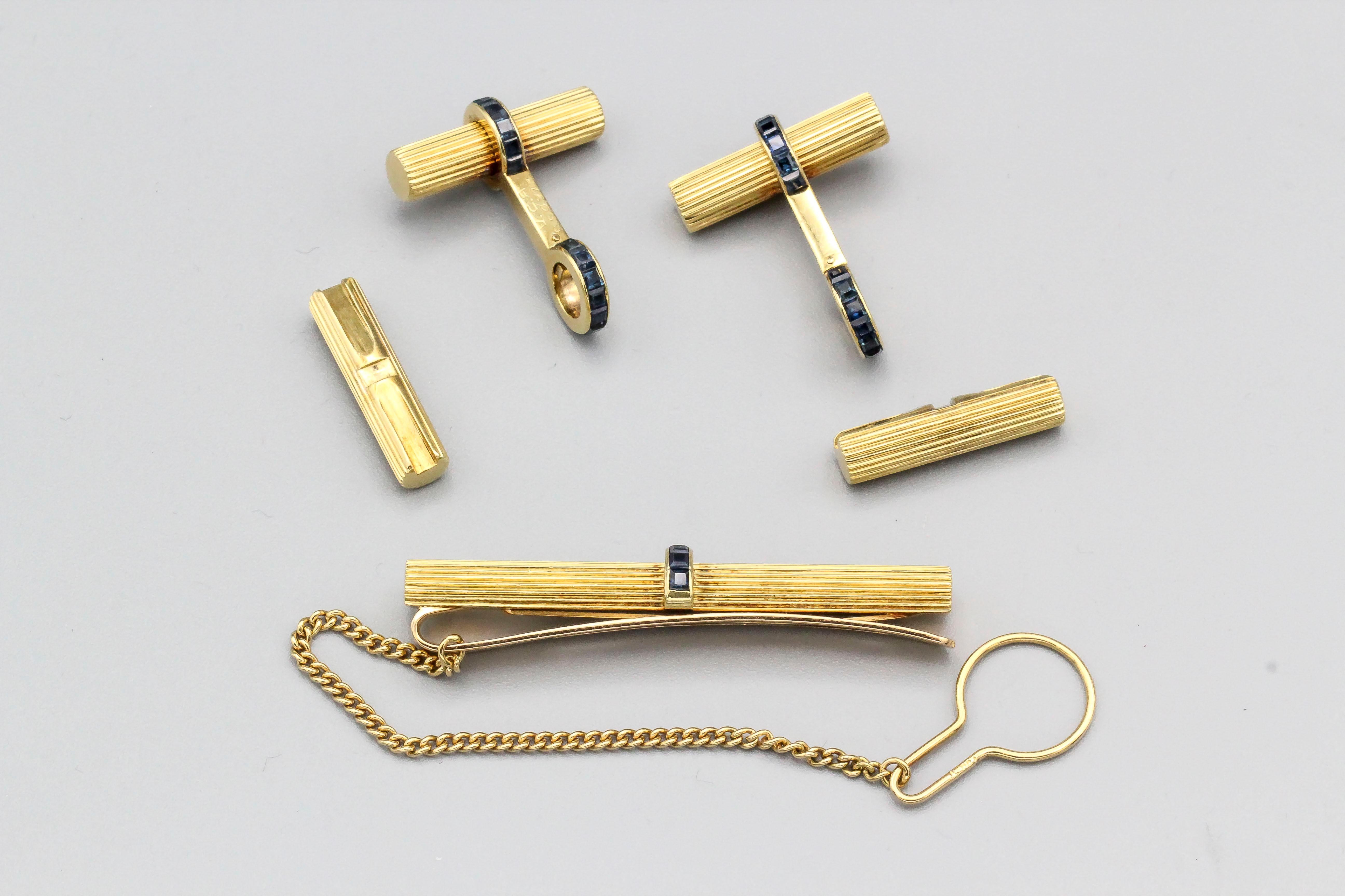 Very handsome sapphire and 18K yellow gold bar cufflinks and tie bar by Van Cleef & Arpels, circa 1960s-70s. They resemble ribbed gold bars, with rich blue sapphires. One end of the bars twists off for ease of installation. Tie bar follows same