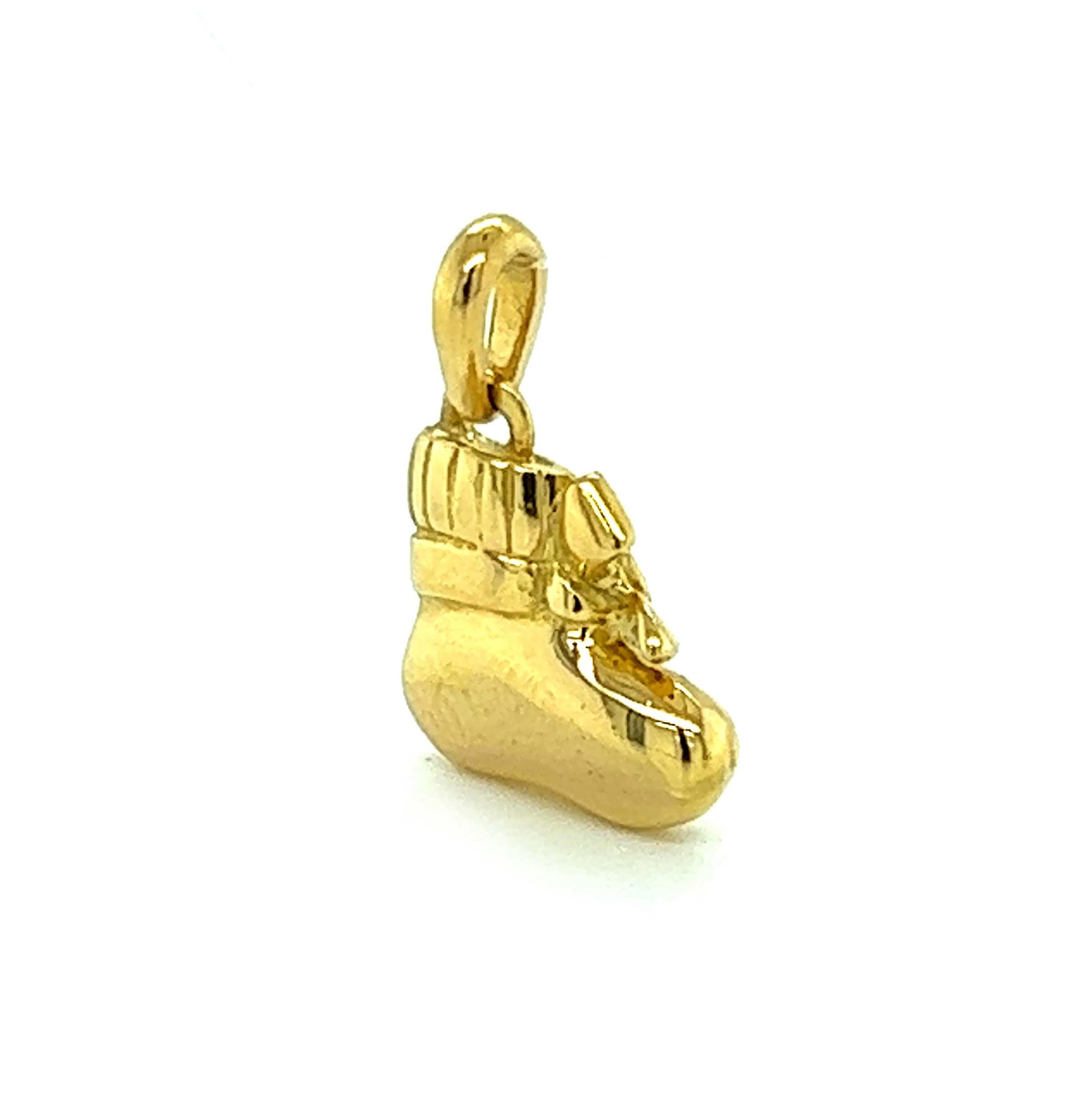 This adorable authentic charm or pendant is by Van Cleef & Arpels, it is crafted from 18k yellow gold with a polished finish featuring a baby girl booty with a ribbon bow tie accented with a small round cut sapphire gemstone. The charm comes with an