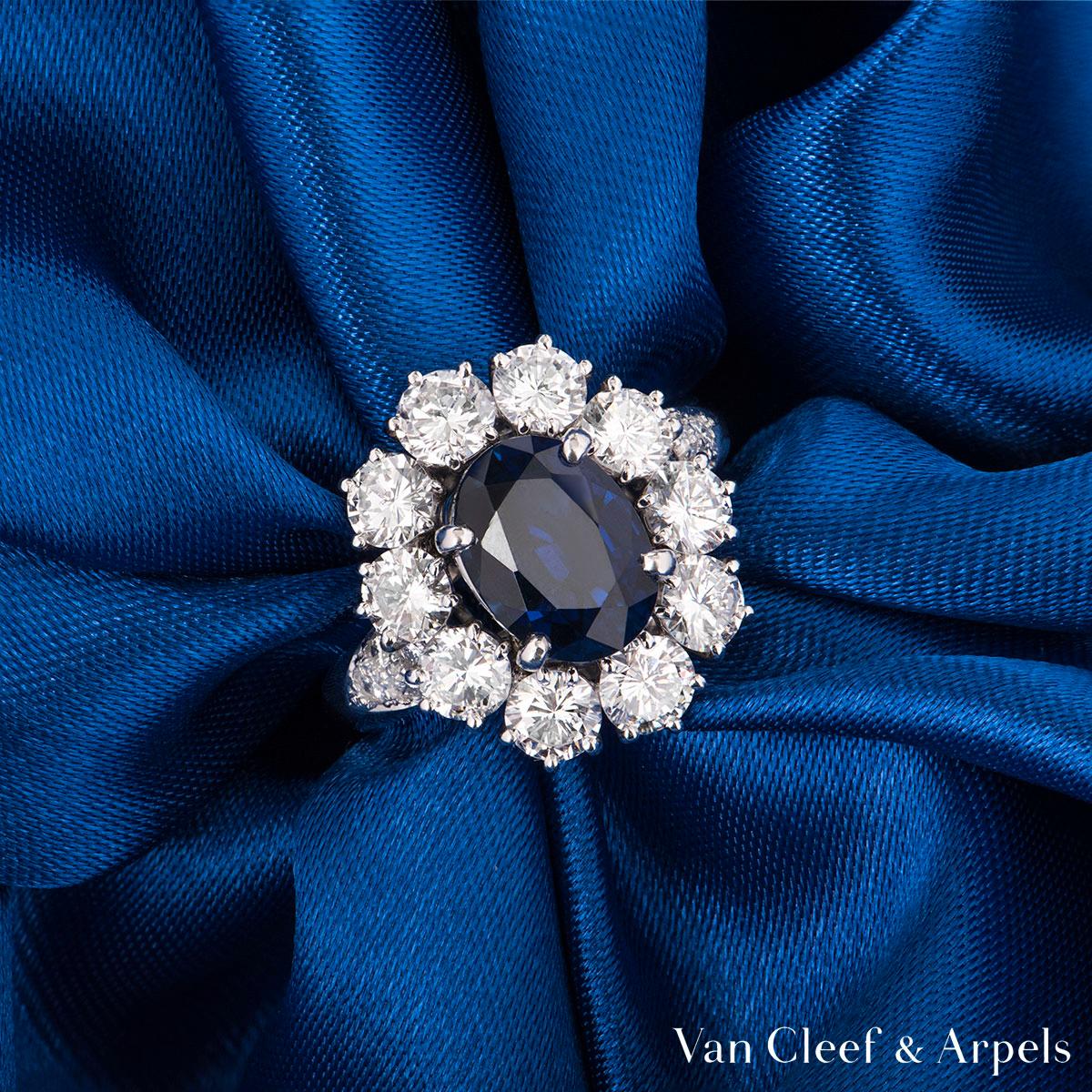 An 18k white gold sapphire and diamond ring by Van Cleef & Arpels. The ring is set to the centre with a 2.48ct natural oval cut sapphire, accentuated by a halo of 12 round brilliant cut diamonds and a further 5 on each side of the mount with a total