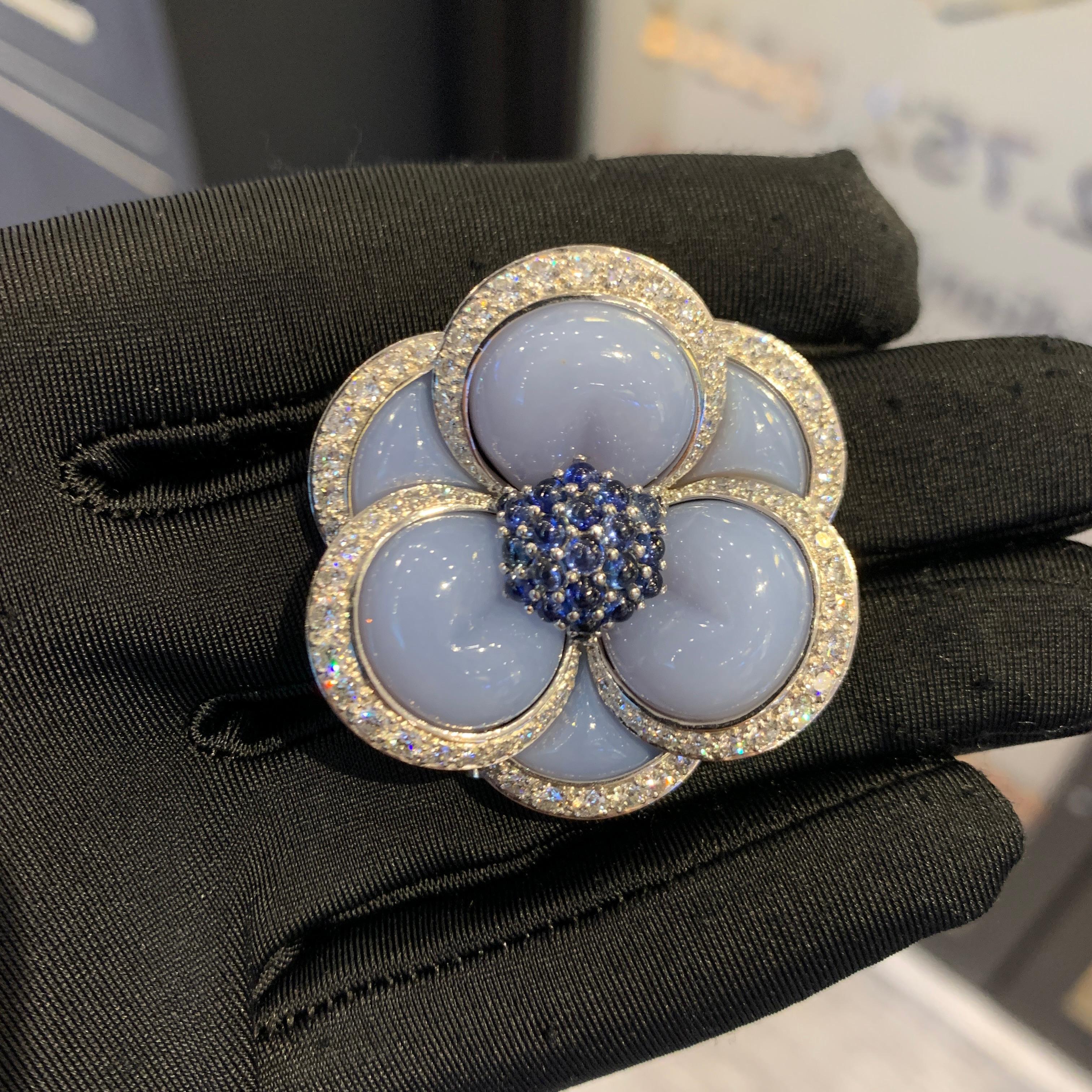 Van Cleef & Arpels Sapphire & Chalcedony Flower Brooch 

A brooch featuring six blue chalcedony petals, 23 round cabochon sapphires, and approximately 3.30 carats of 78 round cut diamonds. 

Measurements: 1.25