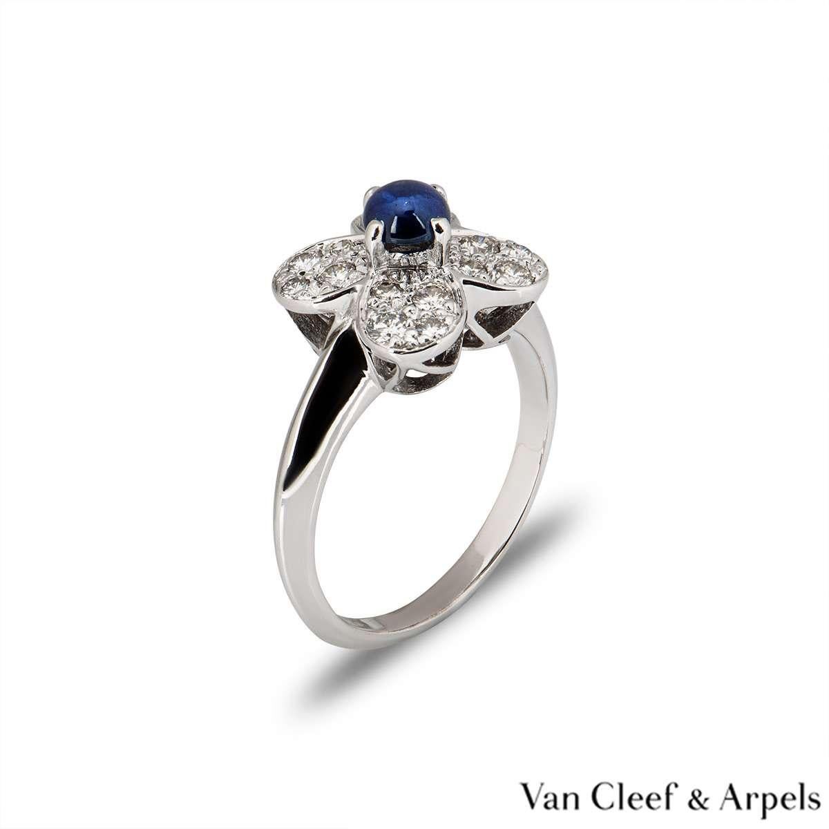 A beautiful 18k white gold Van Cleef & Arpels diamond ring from the Alhambra collection. The central flower motif is set with a single claw set blue cabochon cut sapphire. The surrounding petals of the flower are pave set with round brilliant cut