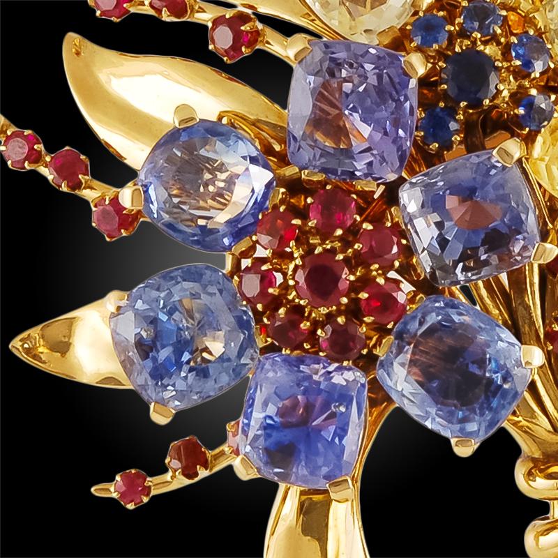 A vintage Van Cleef & Arpels flower brooch in 18k gold; designed as a bouquet of flowers set with six cushion-cut blue sapphires and four cushion-cut yellow sapphires around clusters of rubies and sapphires.

Signed Van Cleef & Arpels and