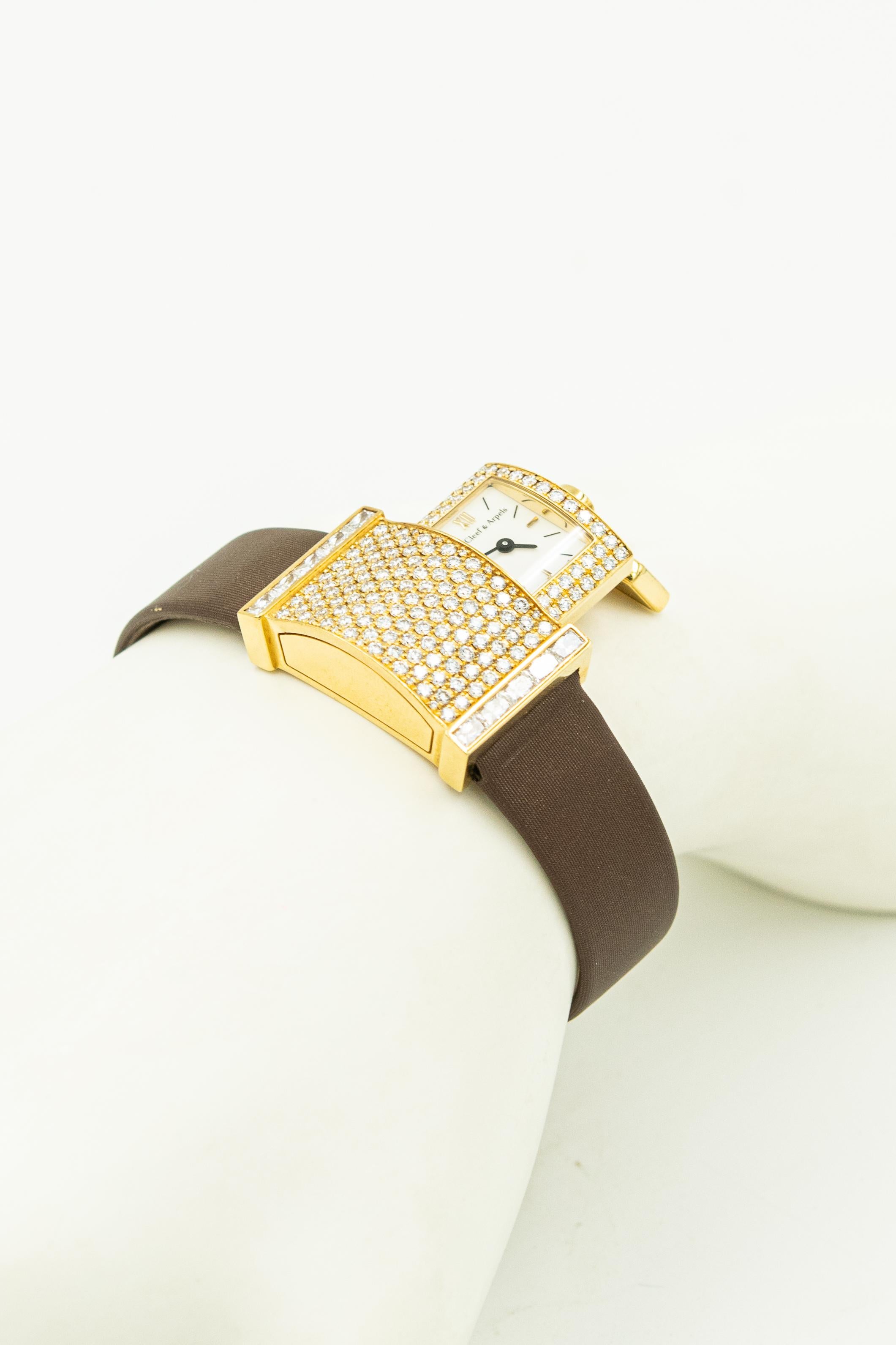 Van Cleef & Arpels Secret Pavée Diamond 18k yellow ladies watch Ref. VCA 1434 Serial #1386101 featuring a rectangular flared case measuring 29 mm x 18 mm. It has a white dial, black markers ,a Swiss quartz movement, hidden within a jeweled drawer.