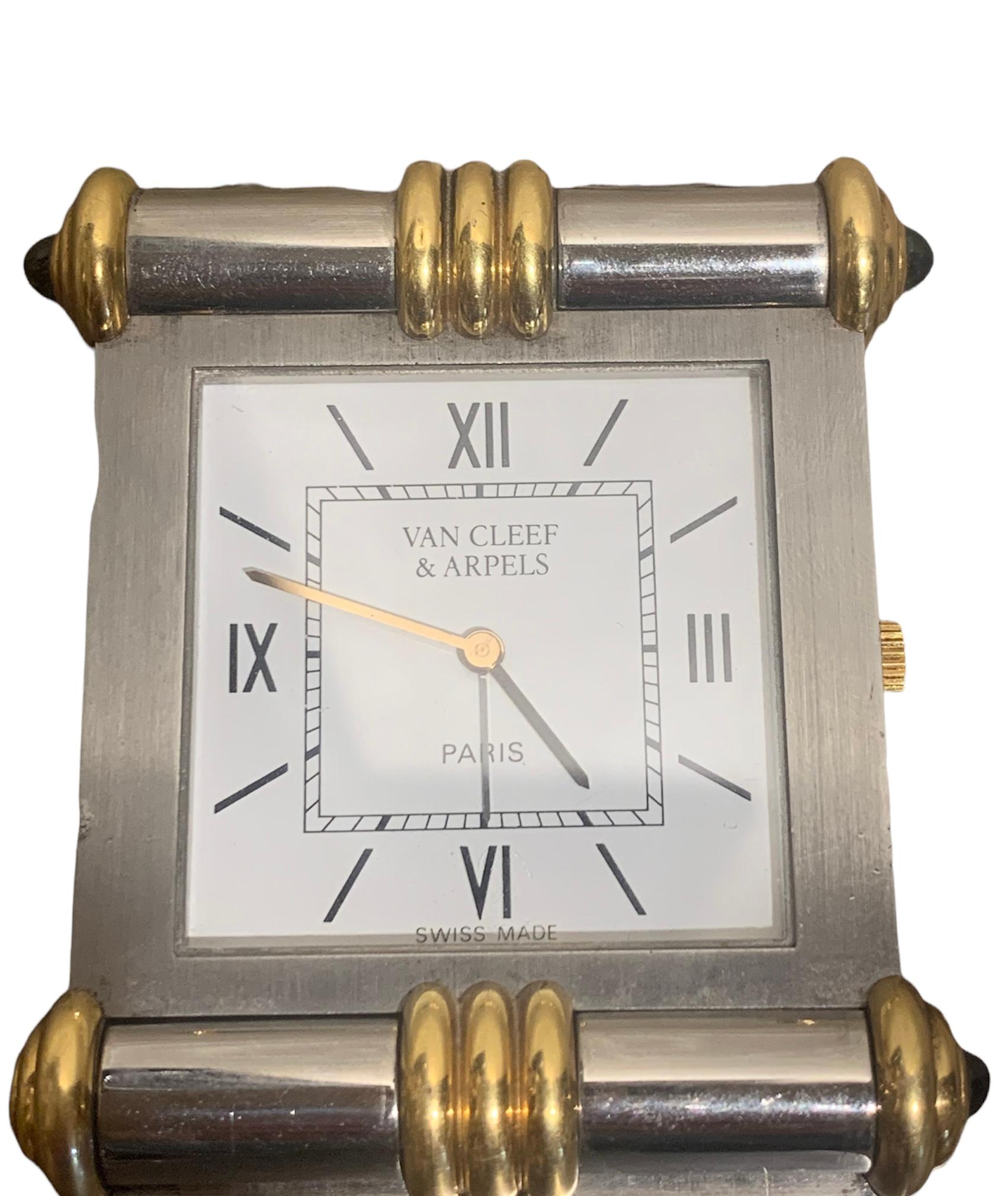 A fine travel clock Van Cleef & Arpels in steel and yellow gold.

Thanks to its articulated plate, it opens to reveal its square dial.

Each corner is set with a blue stone.

Dimensions: 58.18 x 46.09 x 8.10 mm (2.290 x 1.814 x 0.320
