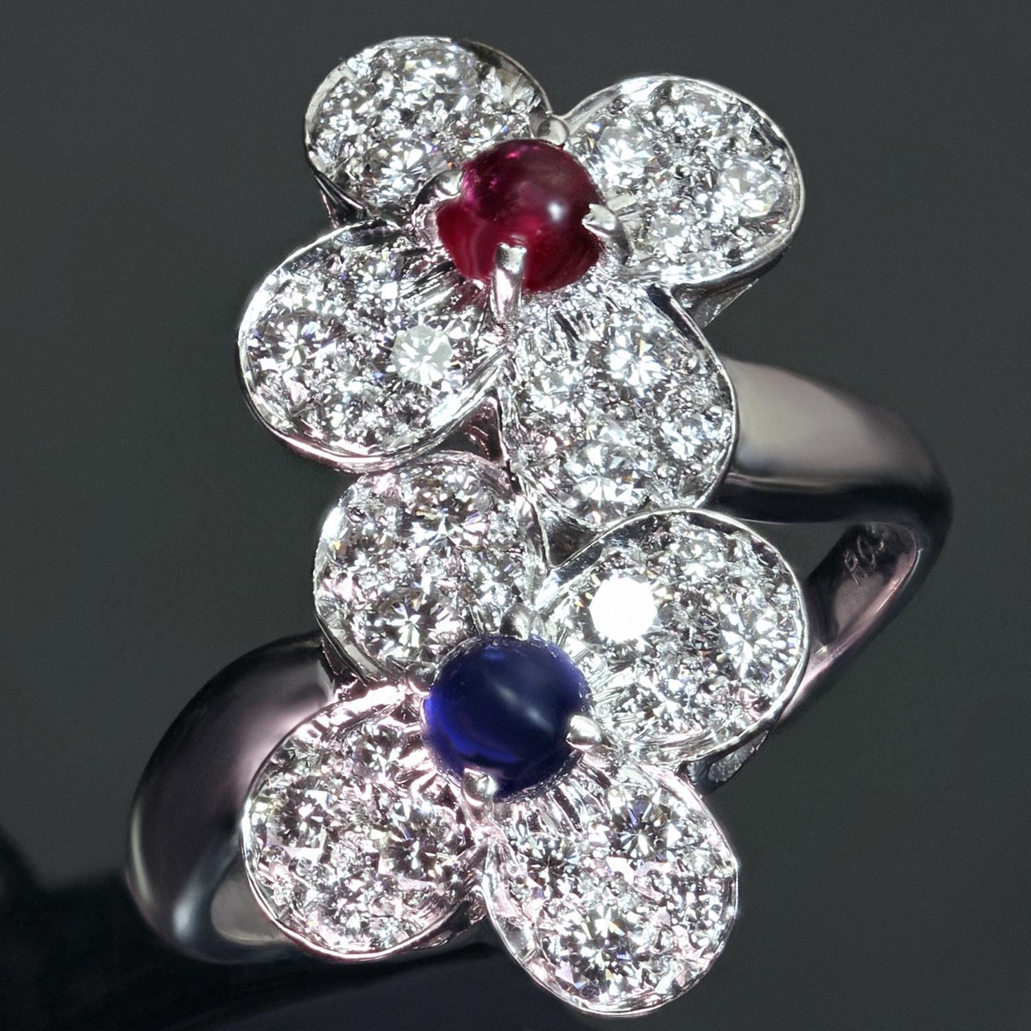 This stunning Van Cleefs & Arpels ring from the classic Trefle collection is crafted in 18k white gold and features a double clover flower motif set with a round cabochon blue sapphire and red ruby and round brilliant D-F VVS1-VVS2 diamonds weighing