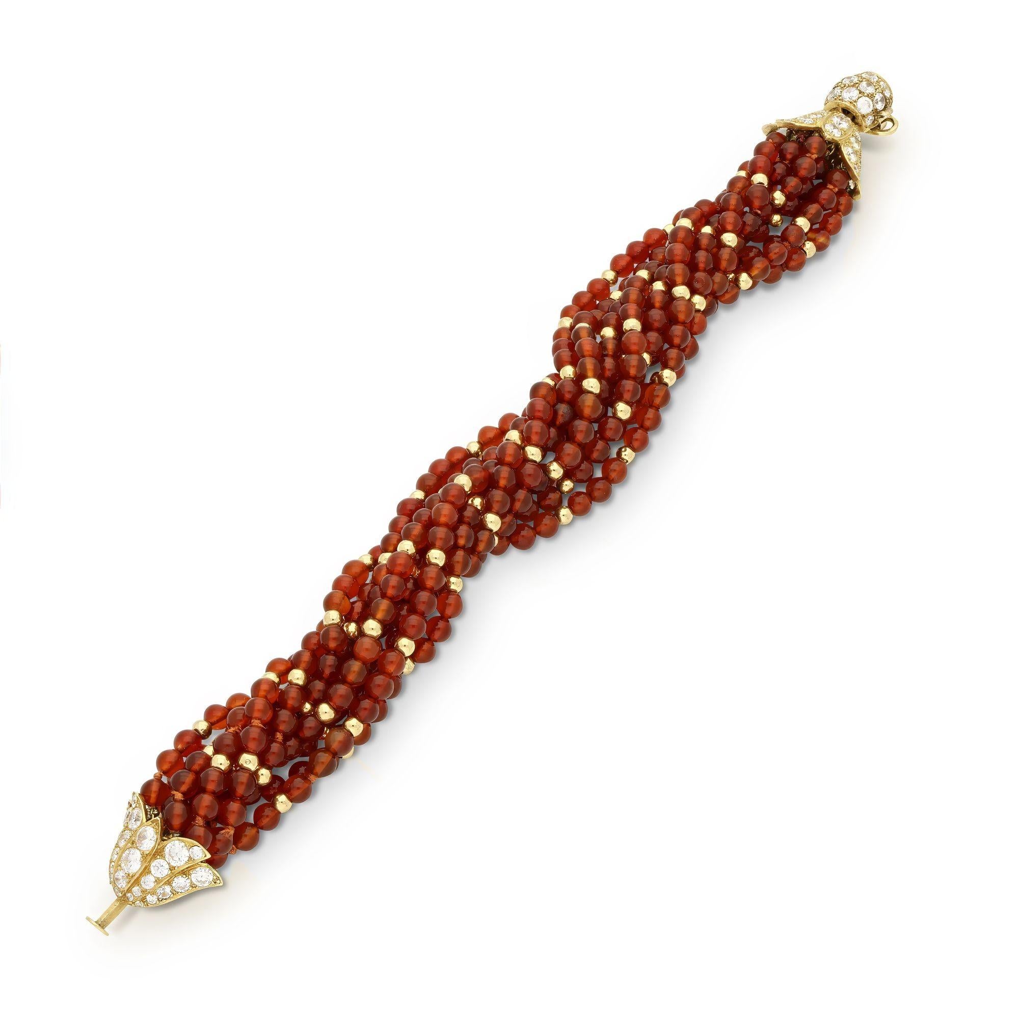 A vintage carnelian bead and diamond set bracelet by Van Cleef & Arpels, circa 1970. The ten strand bead bracelet, each strand has a row of uniform carnelian beads intersperced with 18ct yellow gold beads ever three. The clasp is an 18ct yellow gold