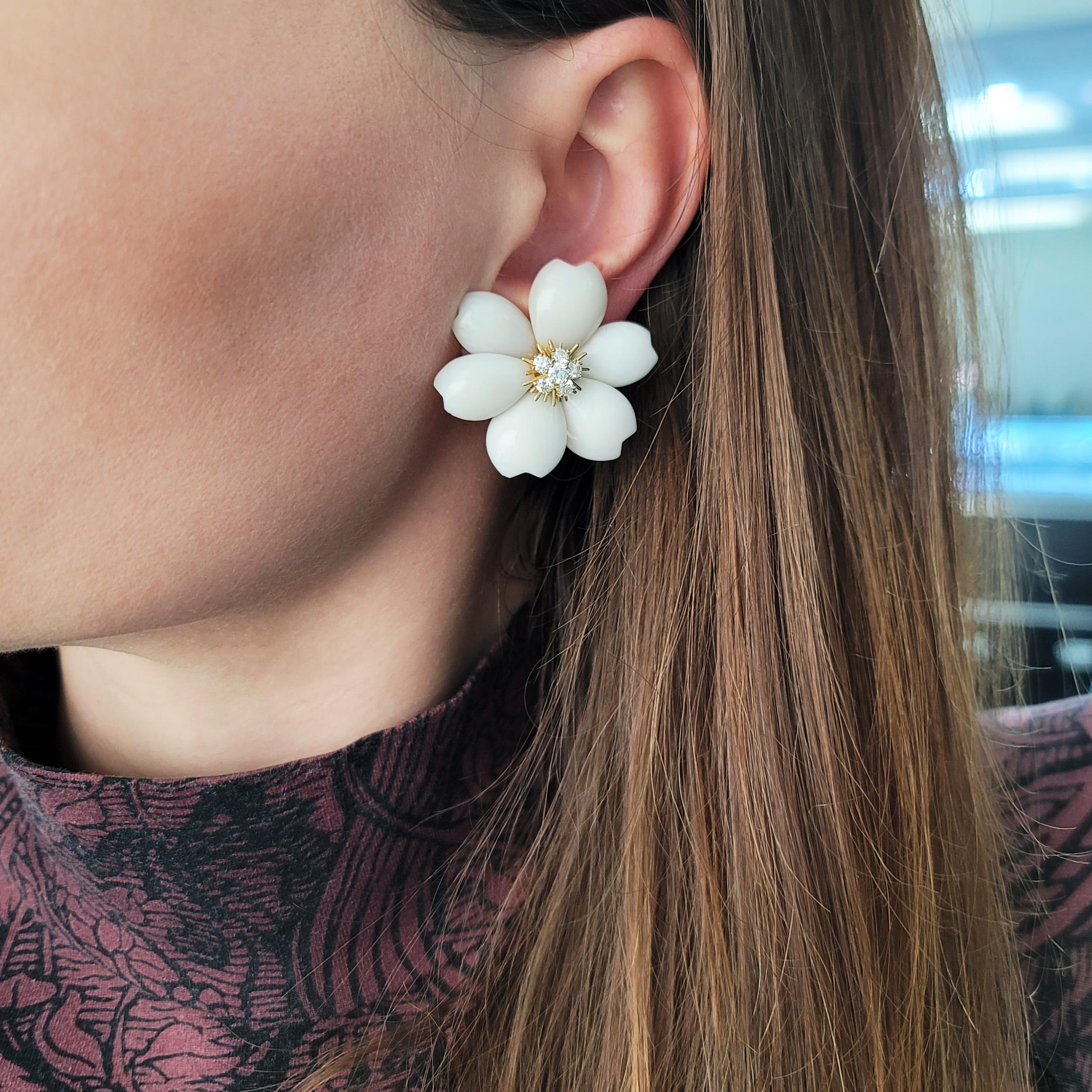 Van Cleef & Arpels White Coral 'Rose de Noel' Ear Clip Earrings In 18k Yellow Gold (Medium).
The earrings feature flower design with 12 white coral petals and 18k yellow gold and diamond centers. There are 12 round brilliant cut diamonds with total