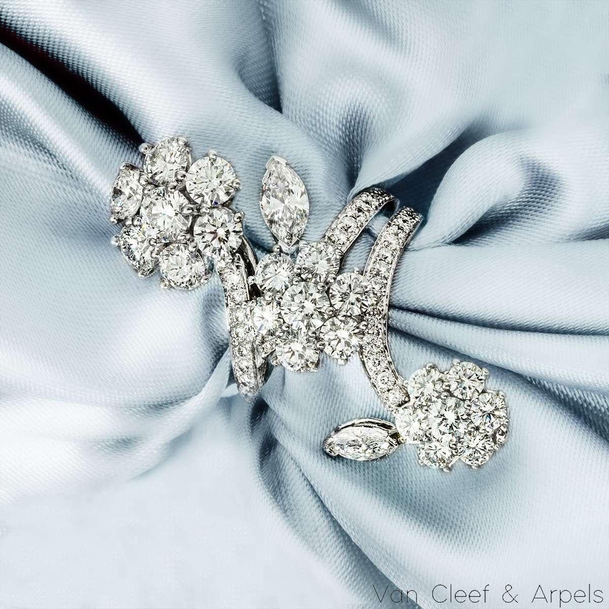 Un magnifico anello con diamante in oro bianco 18k della rinomata collezione Folie des Prés di Van Cleef & Arpels. Disegnato con un delicato motivo floreale, ogni fiore è composto da sette diamanti rotondi taglio brillante, splendidamente completati