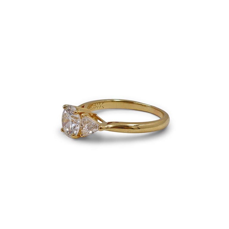 Authentic Van Cleef & Arpels ring crafted in 18 karat yellow gold and set with a GIA certified 1.05 carat round brilliant cut diamond (F color, VVS1 clarity). The classic design is completed by 2 trilliant cut diamonds weighing an estimated .25