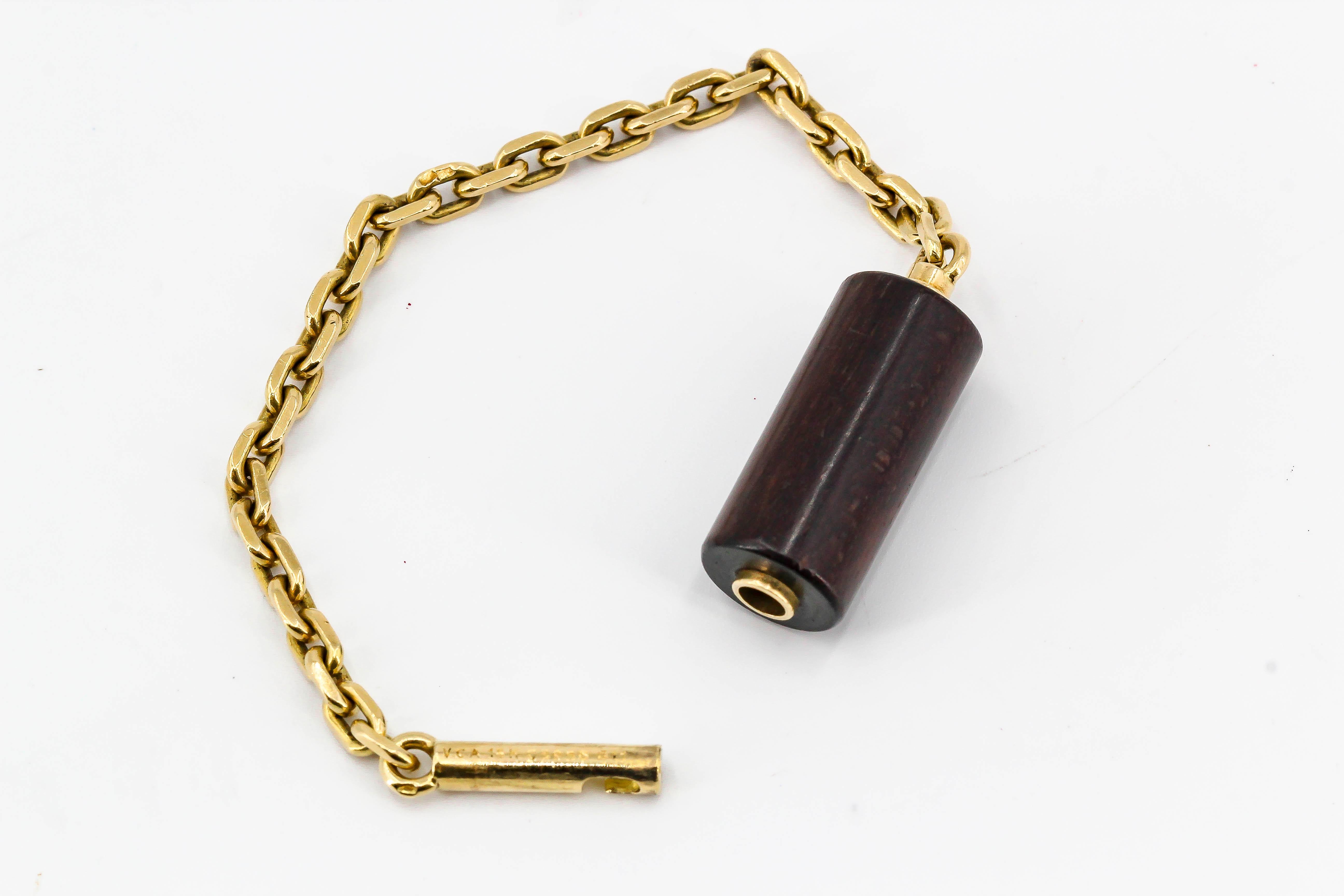 Rare and unusual 18K yellow gold and wood keychain by Van Cleef & Arpels. It features an 18K gold link chain with wood center section. Closure mechanism involves pushing one pin inside and turning it.

Hallmarks: VCA, French 18K gold assay mark,