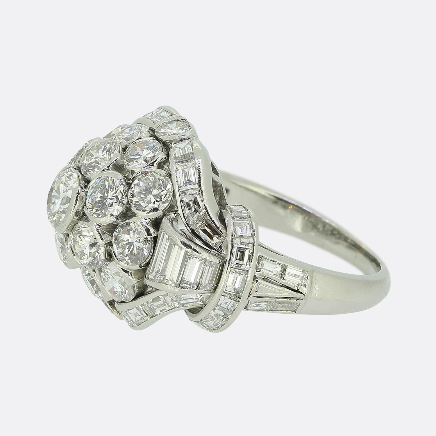Hier haben wir einen sensationellen Diamant-Cluster-Ring des weltbekannten Luxusschmuckdesigners Van Cleef & Arpels.  Das aus Platin gefertigte Schmuckstück zeigt einen kuppelförmigen Kopf, der mit drei Reihen runder Brillanten besetzt ist. Dieser