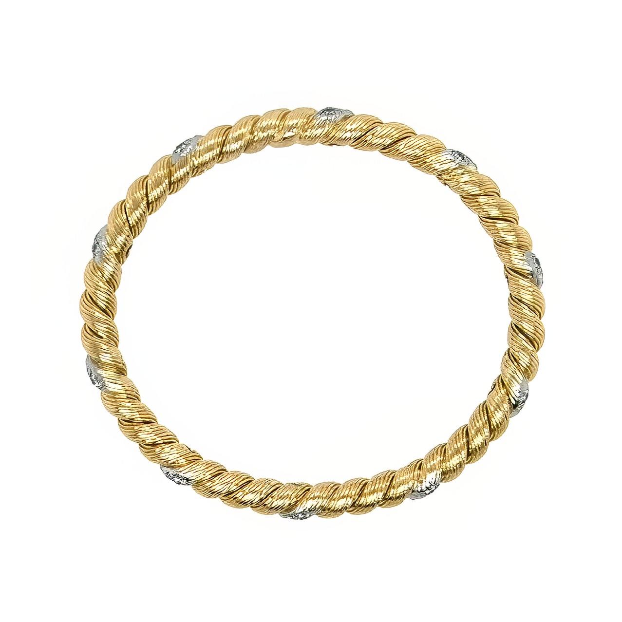 An 18 karat yellow gold, platinum and diamond bracelet, Georges Lenfant, Van Cleef & Arpels, France.  Designed as gold bangle in a twisted motif, enhanced with 30 platinum set round brilliant cut diamonds in evenly spaced diagonals of three.  Total