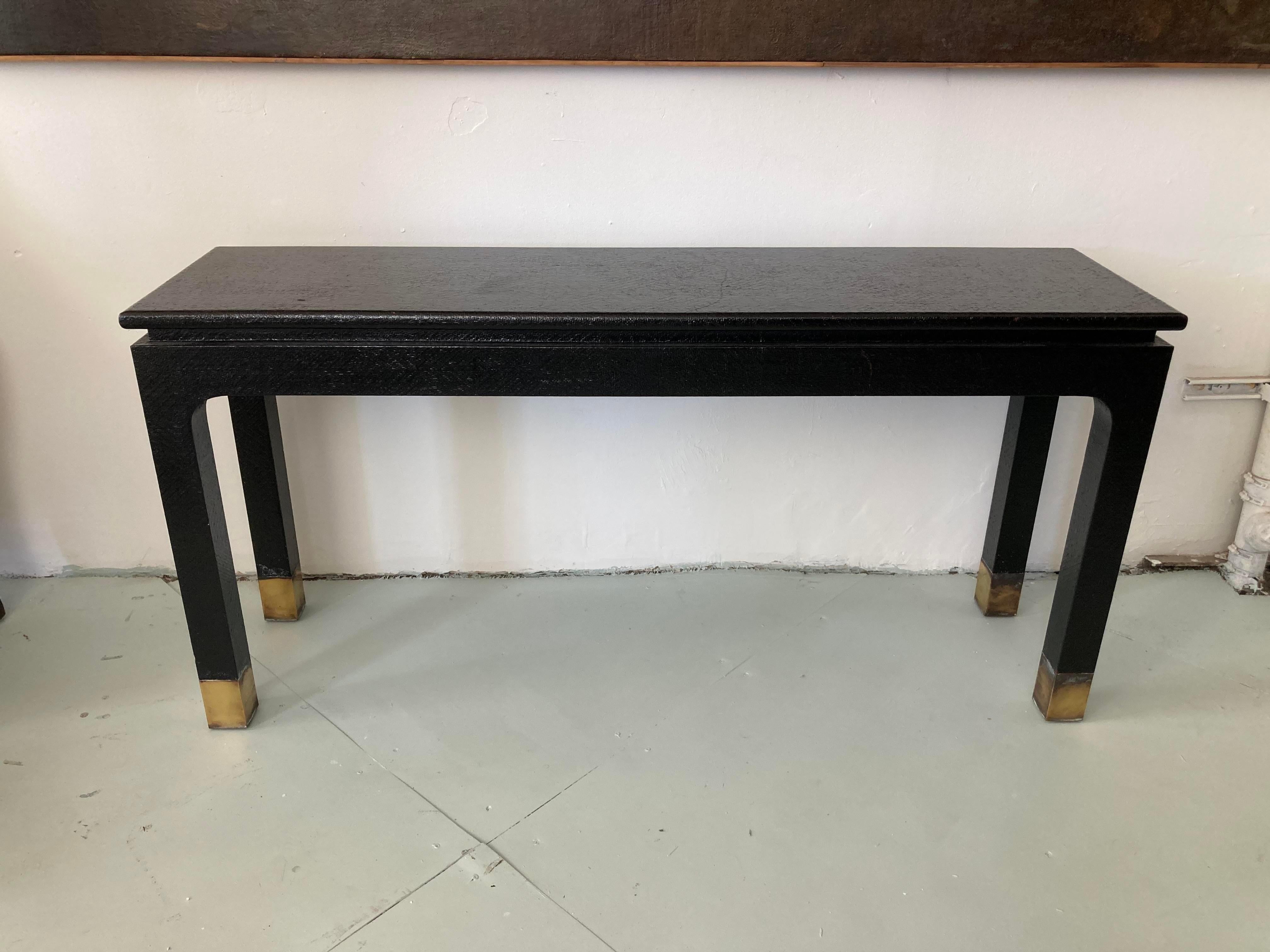 Fantastic original Van Horn console table with Asian details. Black Lacquered Raffia with settle Asian Red undertones similar to an Asian Black Lacquered box. Fabulous Brass leg caps set off the design. 