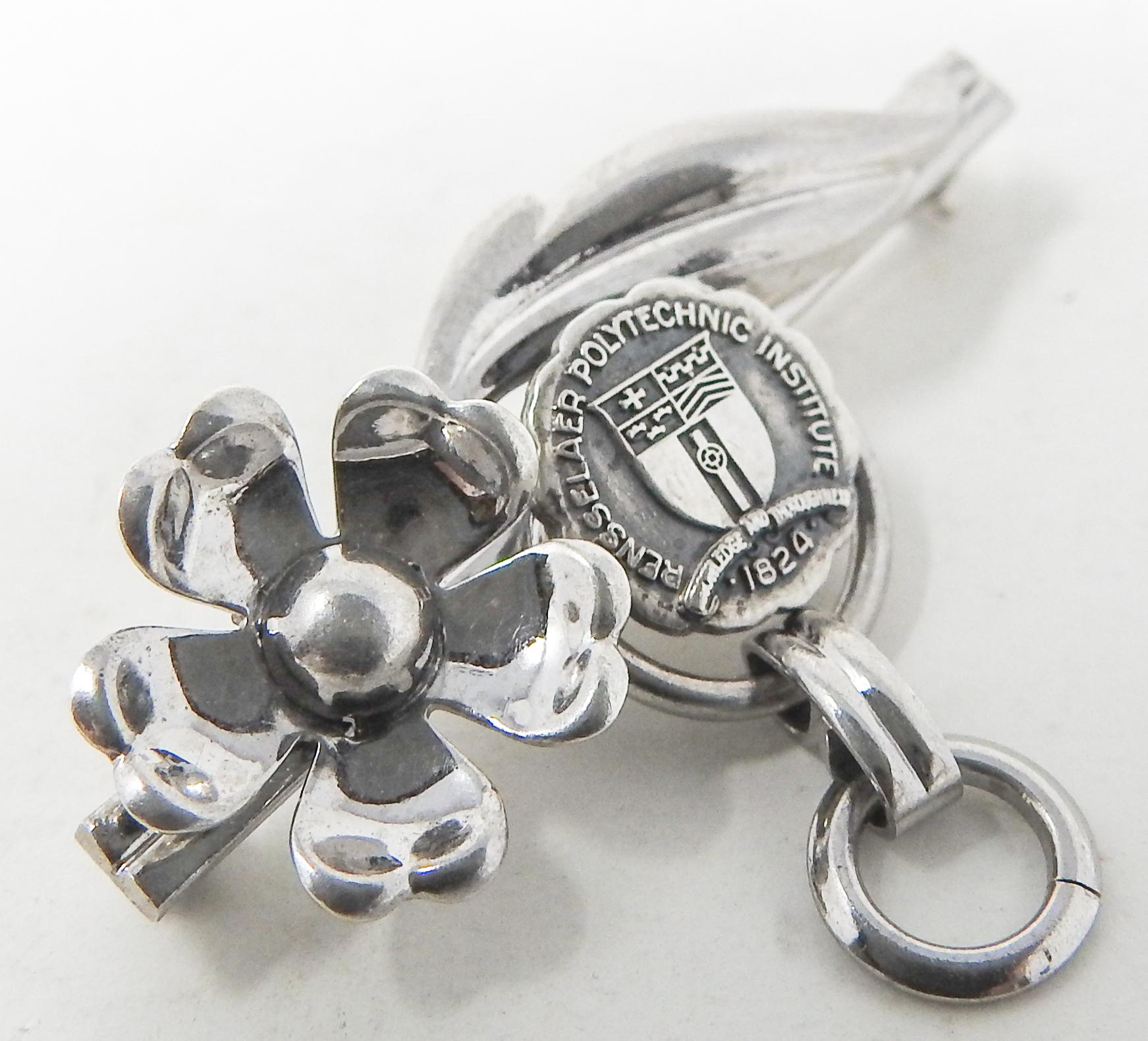 Offering this beautiful sterling silver floral brooch from the Rensselaer Polytechnic Institute. The back is marked VanDell, Sterling. The front has a flower, and a foliate detail with spirals.
