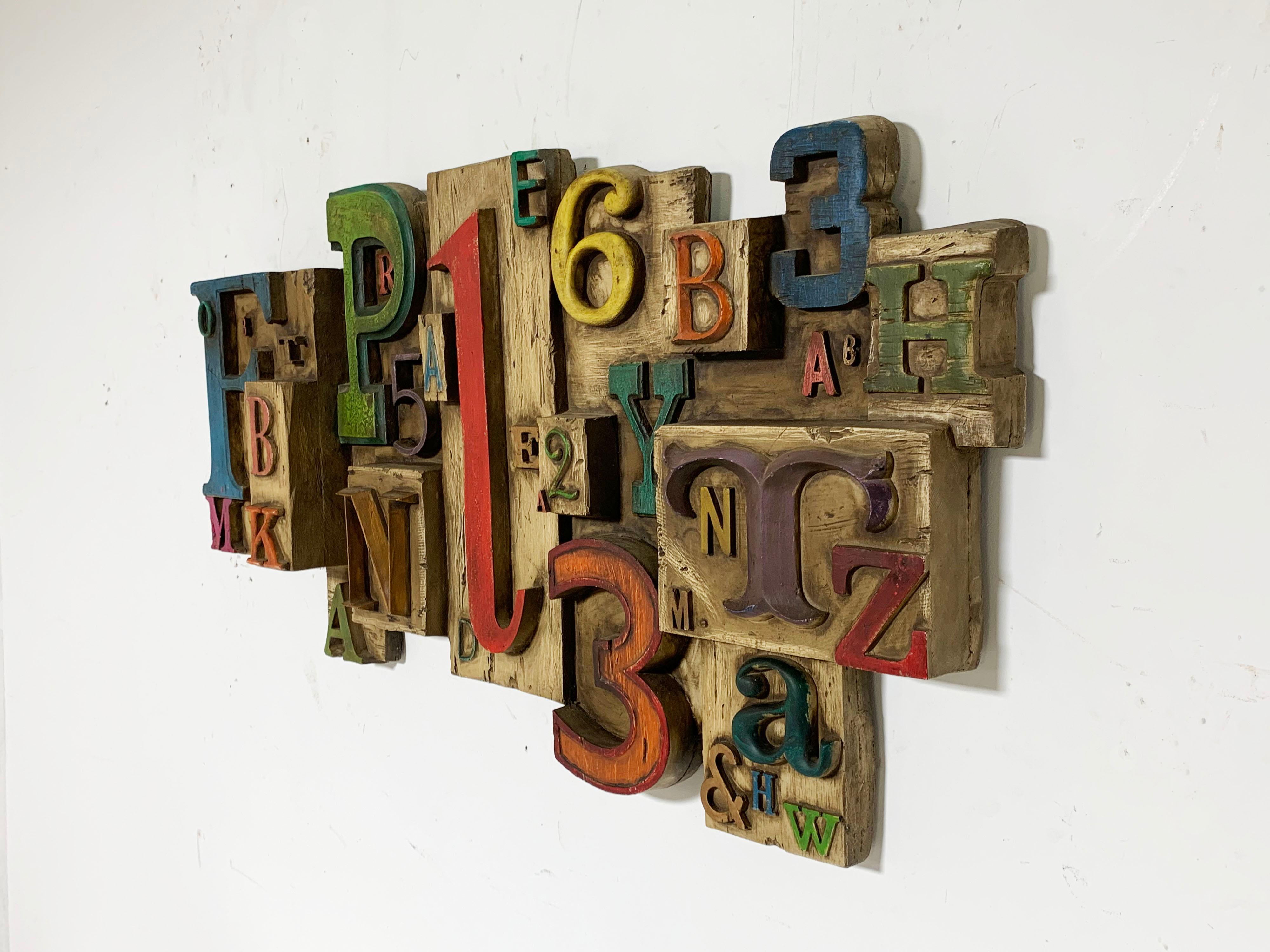 Wall sculpture by Vanguard Studios, dated 1969, composing letters and numbers in a vareity of fonts and sizes, assembled in a multi-dimensional arrangement.