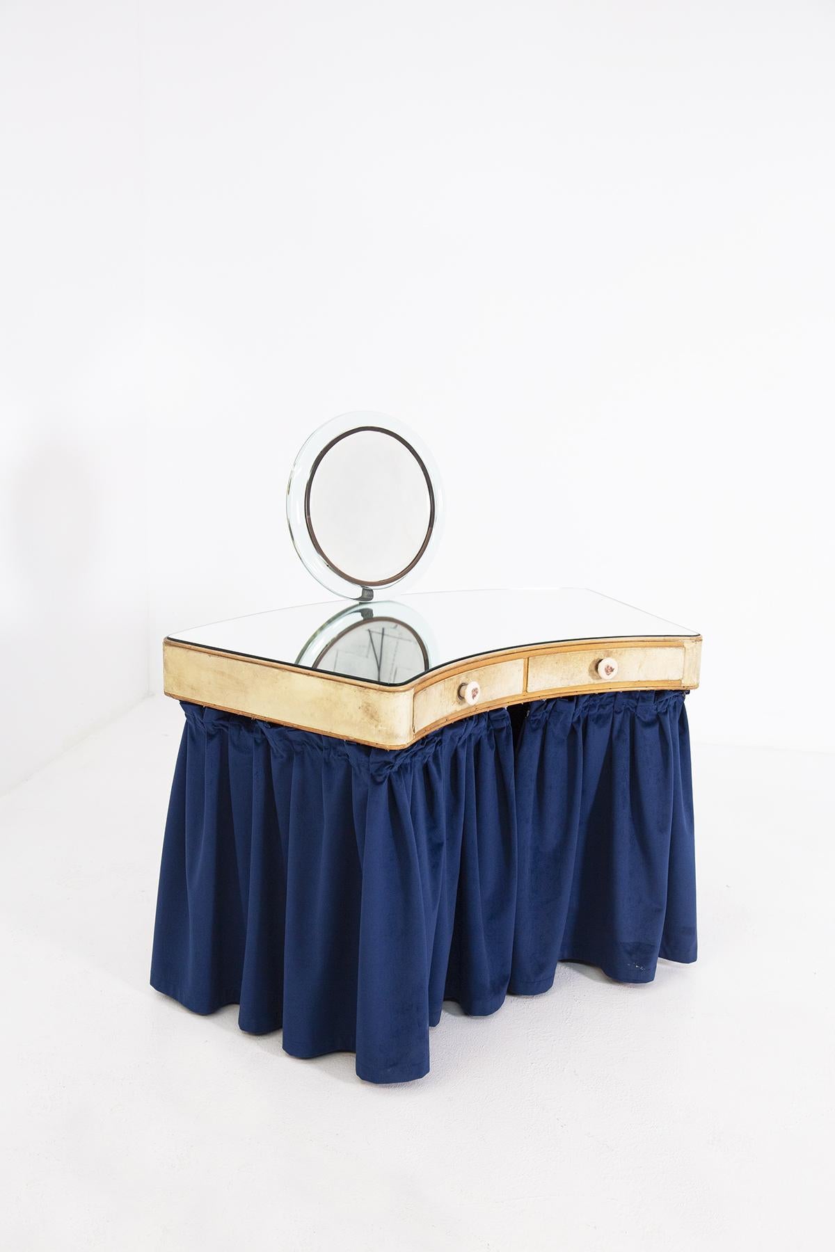 Elegant and refined make-up or vanity desk from the 1940s attributed to Pietro Chiesa.
The bedroom desk is made of various very precious materials. Its top is made of mirrored glass with a flared shape. The central piece in parchment with two