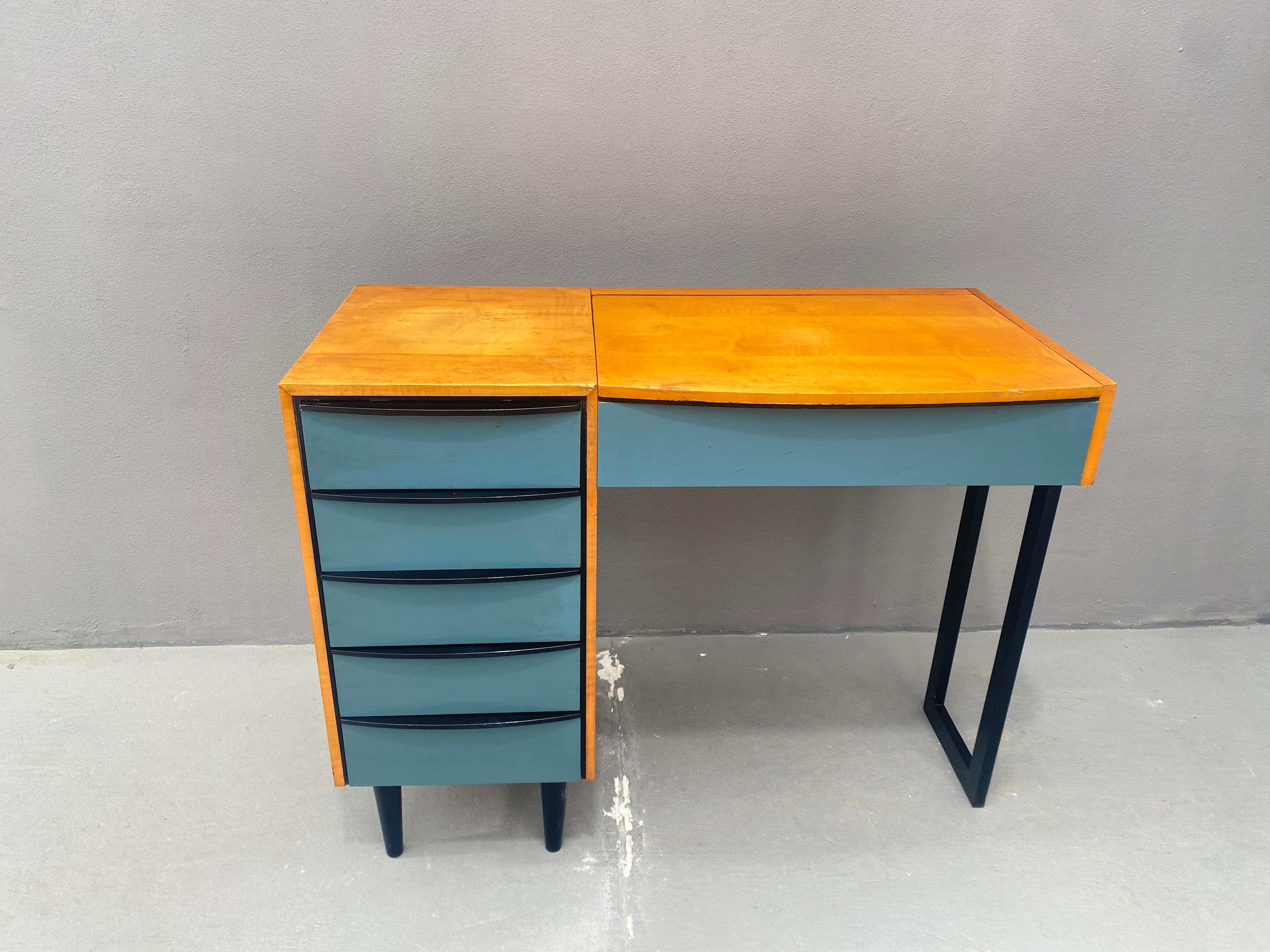 Made in the former Czechoslovakia in the 1970's. This practical vanity desk blends natural wood with painted details, offering ample storage space. The left side features four drawers, perfect for storing cosmetics, jewelry, or other essentials. The