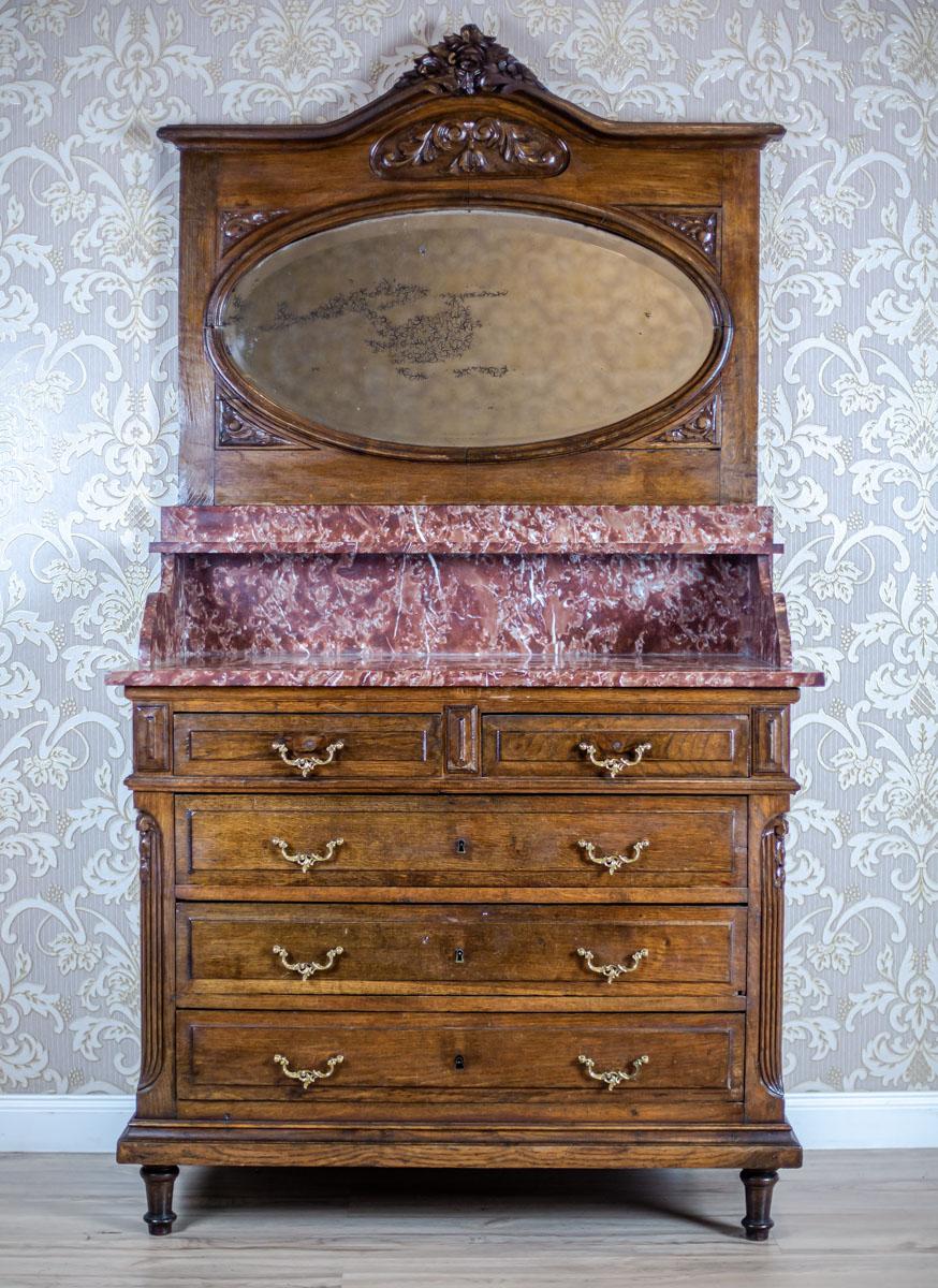 Walnut Vanity Dresser from the Interwar Period with Marble Top

We present you a commode de toilette piece of furniture with an oval mirror and a marble top with a shelf.
Inside the main section are three wide drawers. Another two are under the