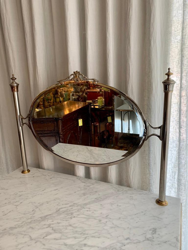 Fantastic antique French chrome and brass vanity with a solid marble table top. Beautiful original oval facetted framed mirror and with many decorative details on the metal table base. Table heigth is 77 cm and the total height is 138 cm.