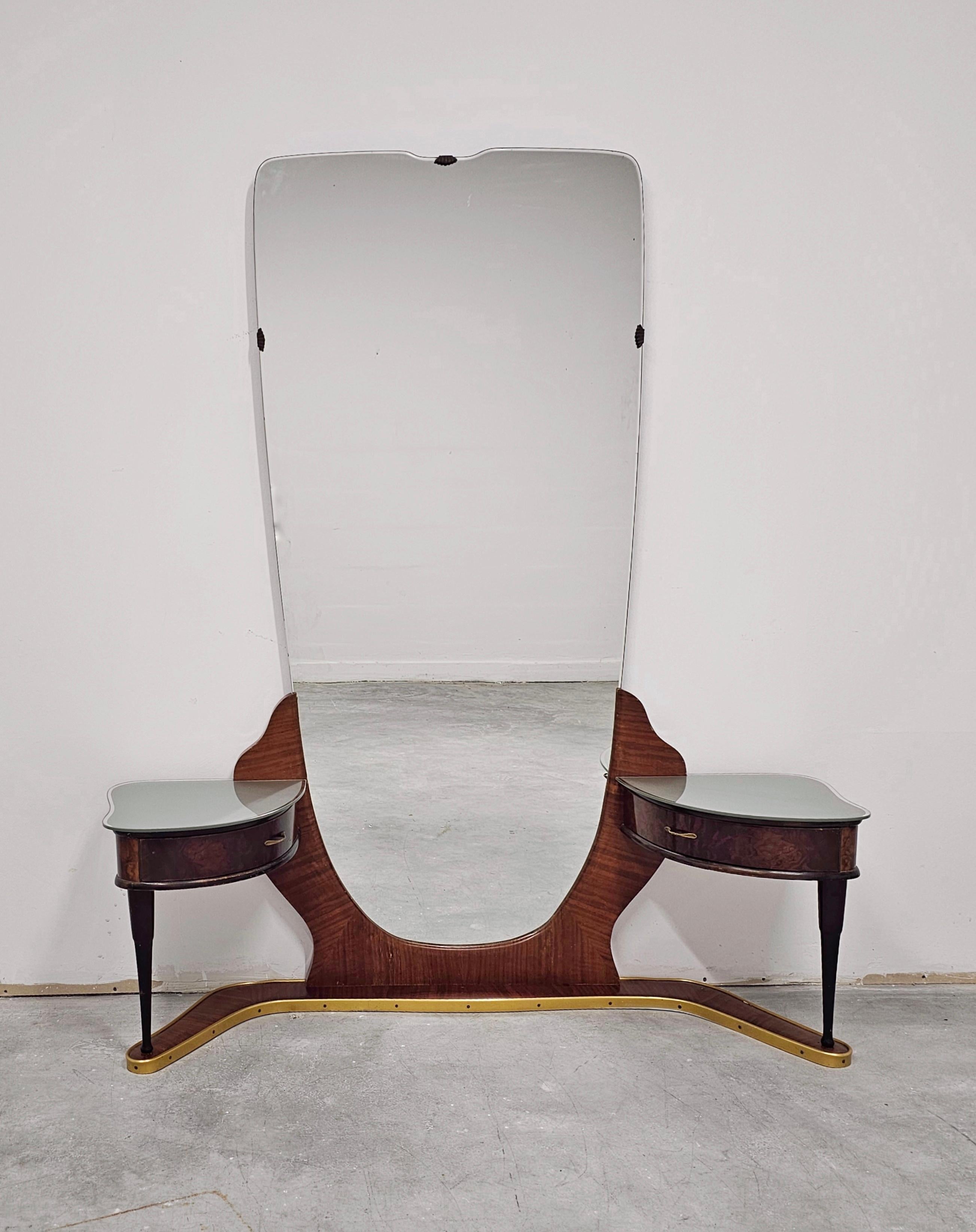 Dans cette annonce, vous trouverez un spectaculaire meuble-lavabo ou miroir coiffeuse de style moderne du milieu du siècle attr. à Cesar. Il est réalisé en ronce de noyer, avec des éléments décoratifs en laiton. Le miroir a une forme unique et