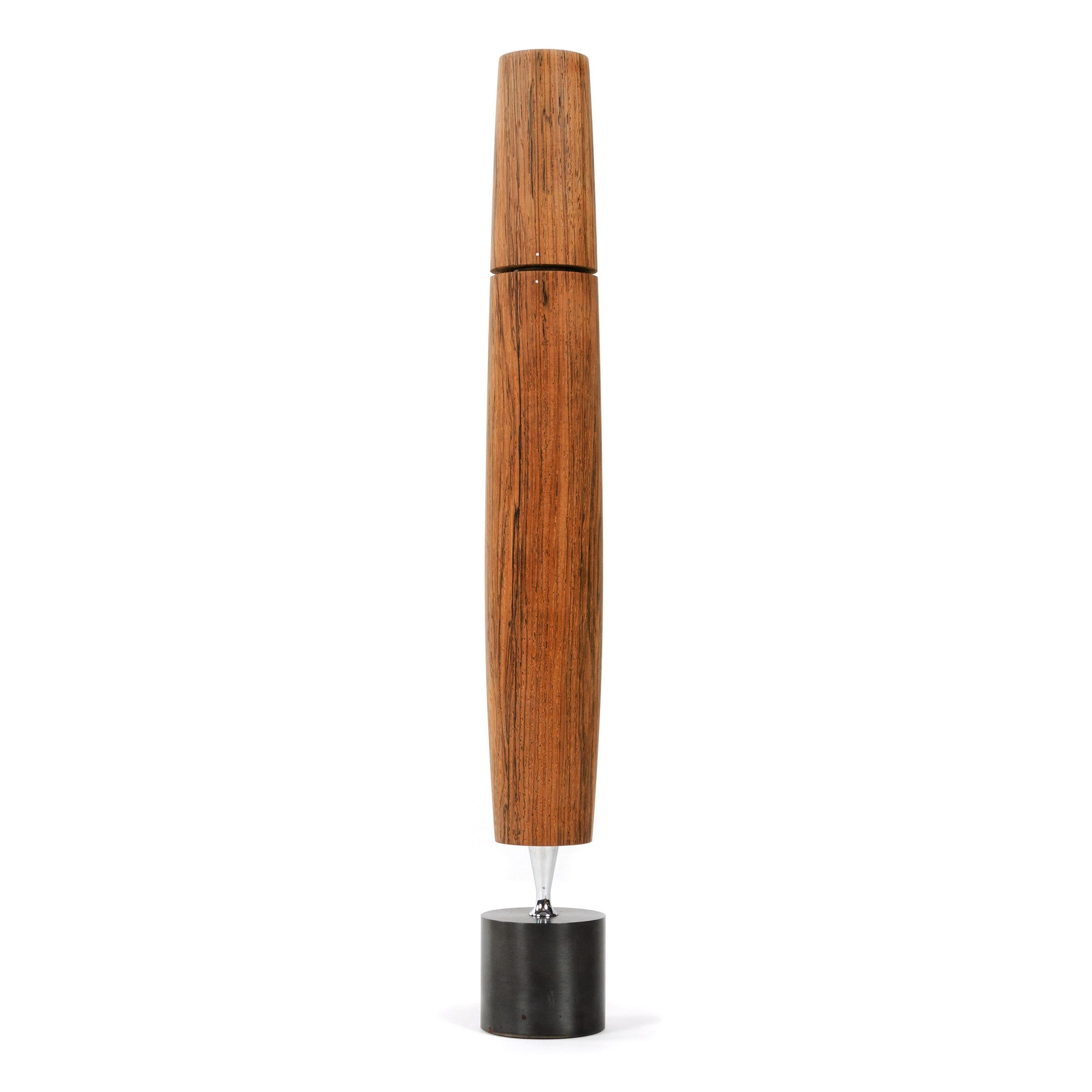 A figured wood 'Varaflame' butane candlestick with chrome stem on a patinated steel base.