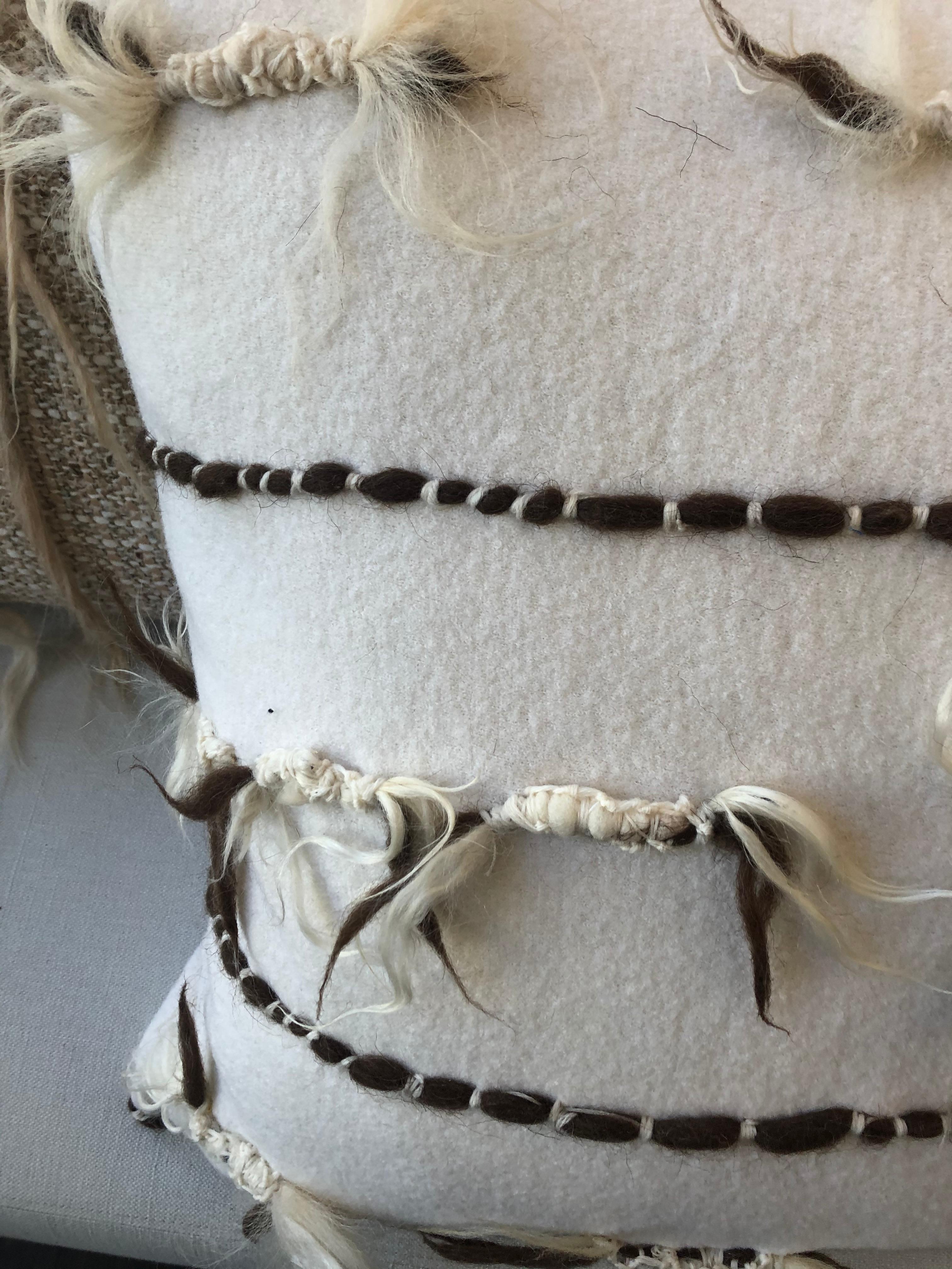Cuscino decorativo in lana intrecciata e lavorata a mano con frange tinte singolarmente che aggiungono consistenza e qualità tattile all'abbellimento. Tutti i cuscini sono unici e utilizzano esclusivamente tecniche di tessitura tradizionali, hanno