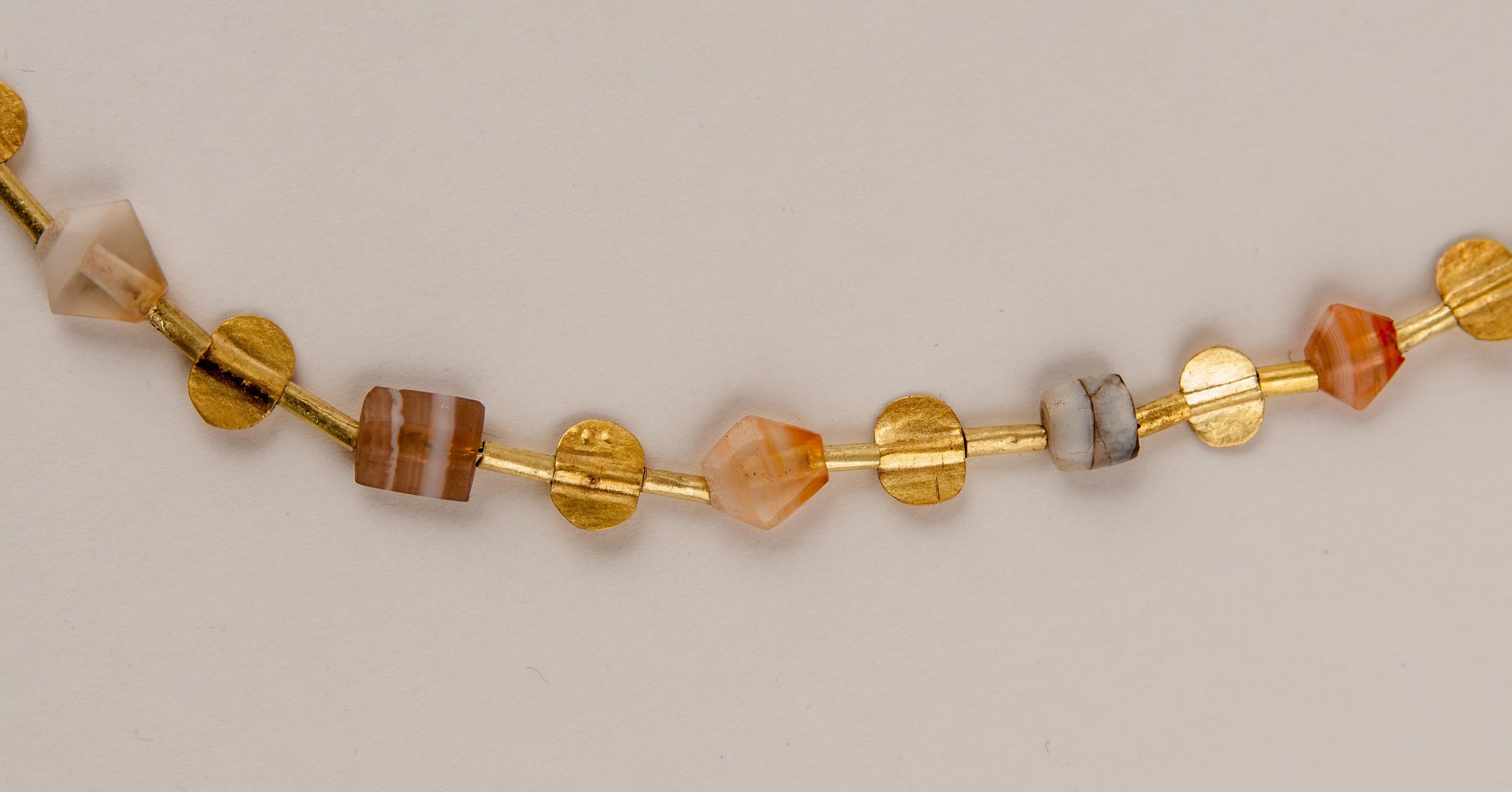 Twenty-three ancient stone beads alternating with twenty-two tabular 20k gold beads. There are forty-six gold tube beads; each stone bead is faced with a pair of tube beads. The stone beads are tabular (except for two barrel beads) rectangular,