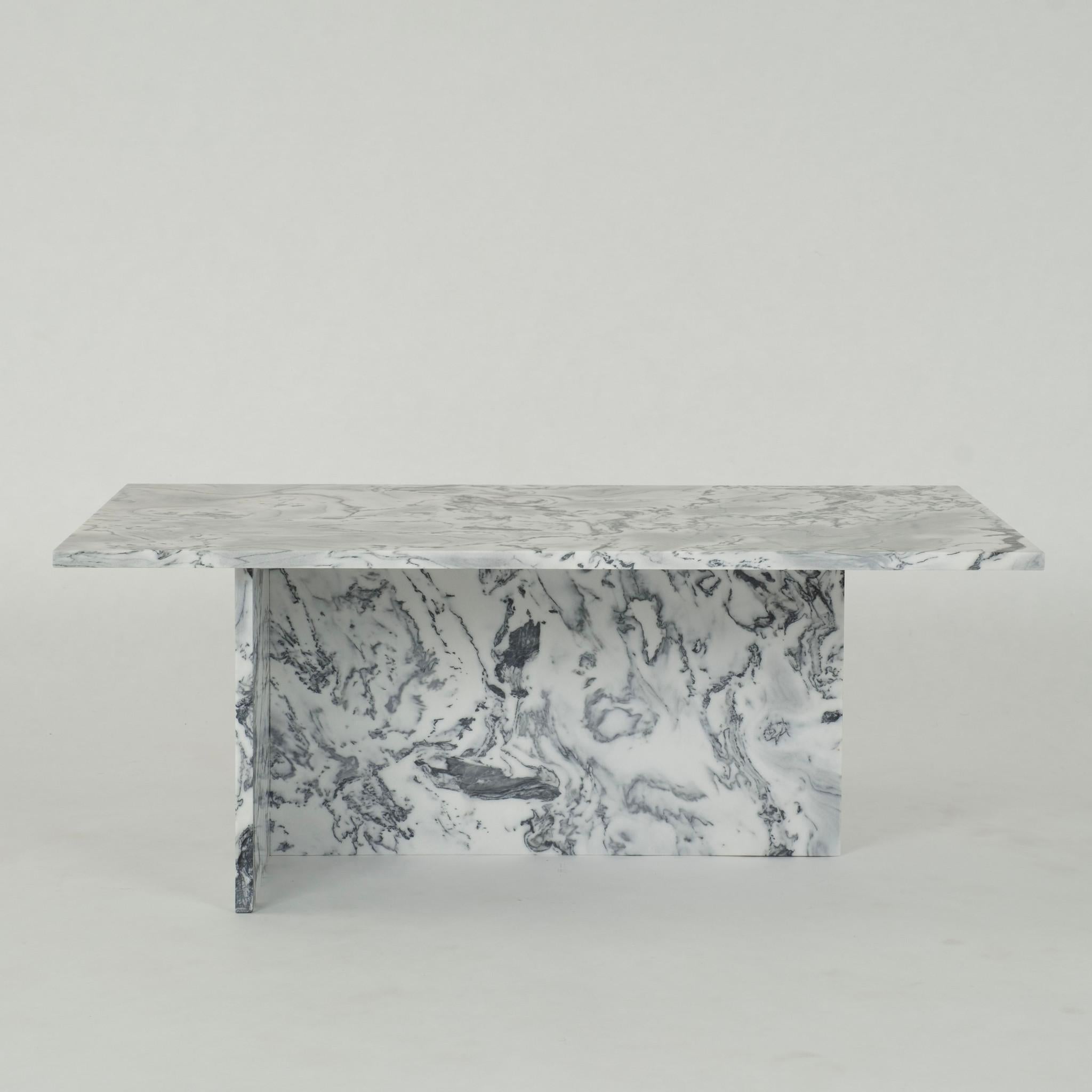 Cette table de cocktail moderne présente un design frappant avec un plateau en marbre blanc et gris soutenu par une base en forme de T.