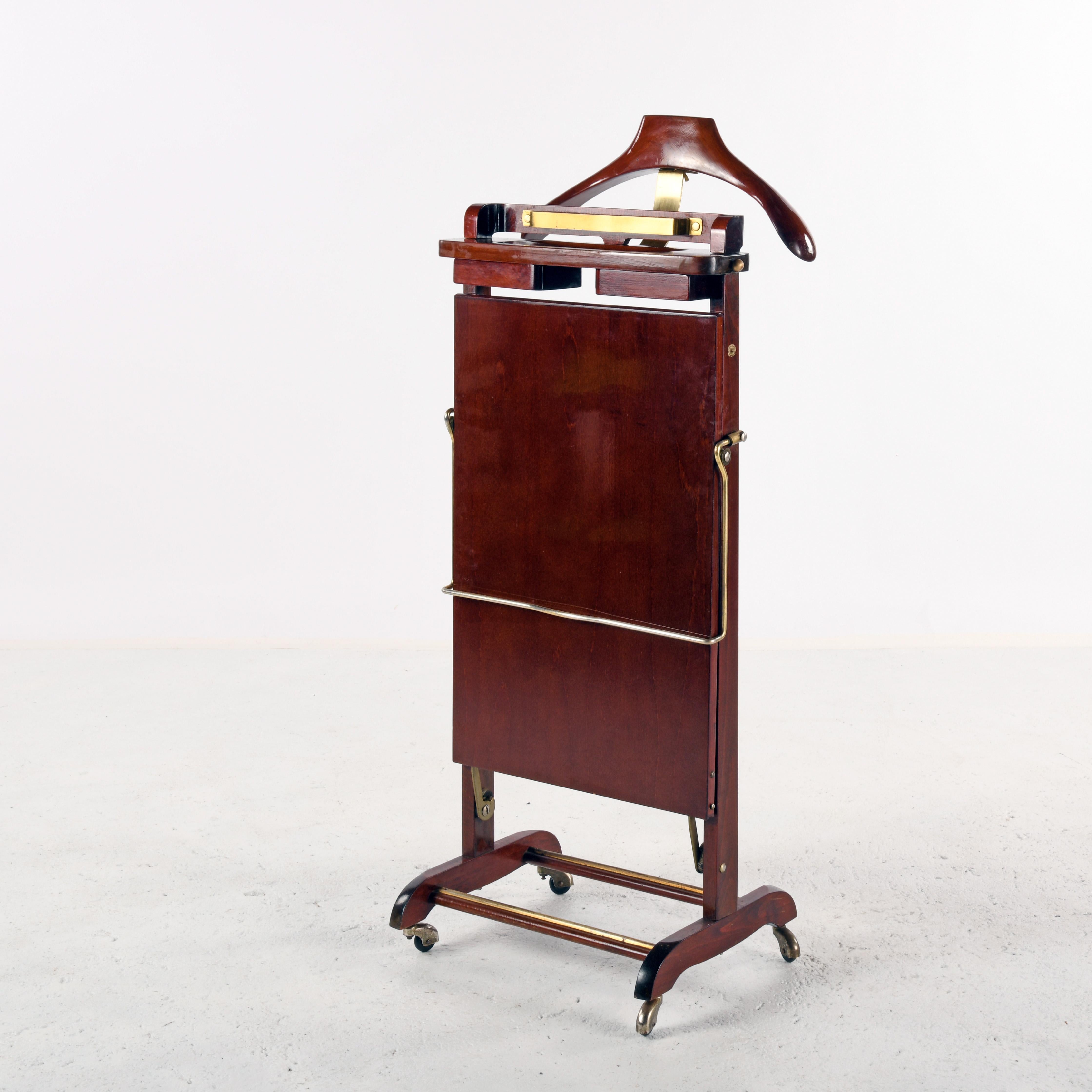 Varnished wooden valet on wheels, produced in Italy in the 1960s by Fratelli Reguitti. Shirt and jacket hanger at the back, trouser press with foam-lined interior to smooth out wrinkles overnight, two retractable felt-lined boxes to hold cufflinks,