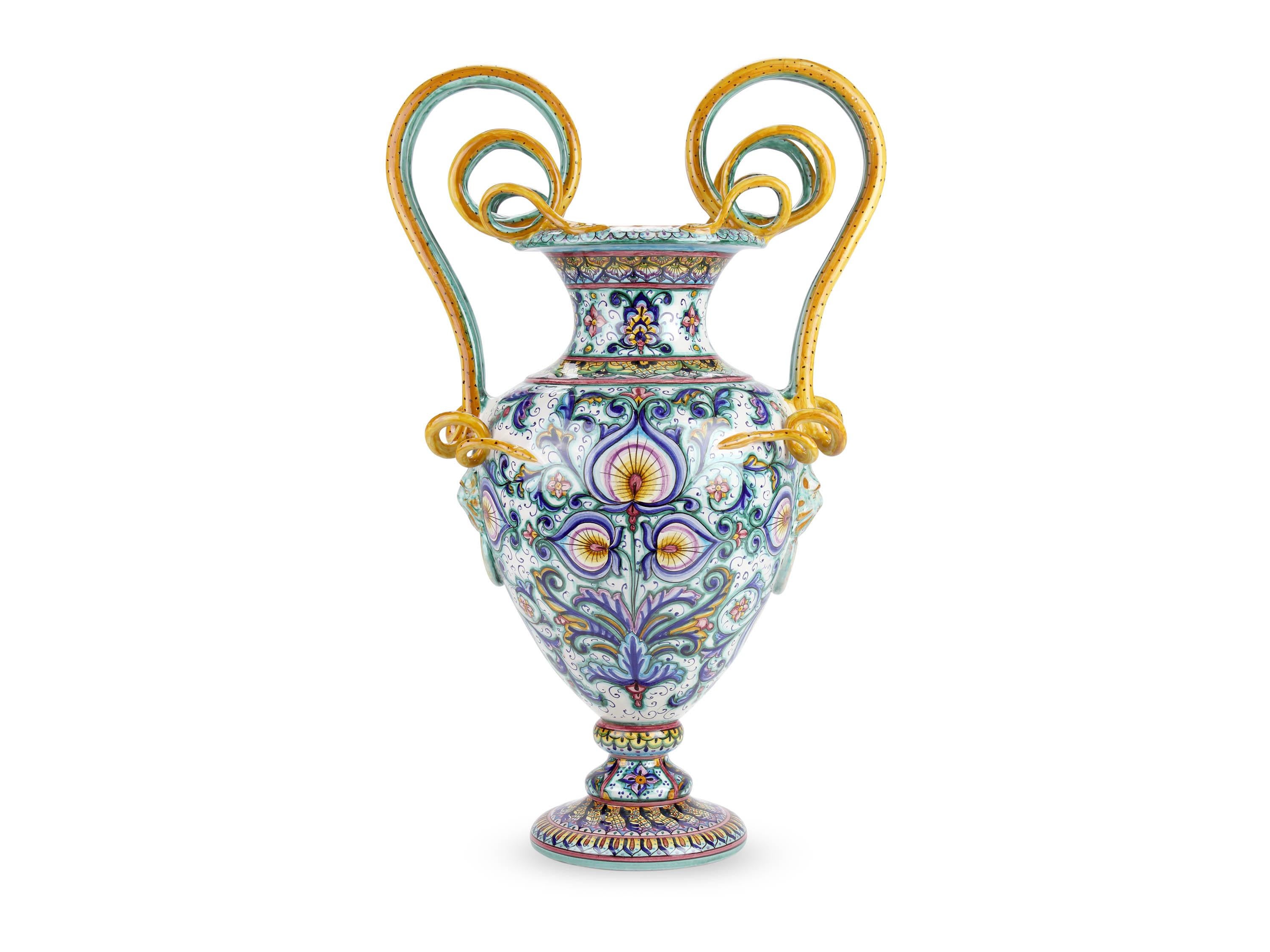 Cette grande amphore luxueuse, en majolique fabriquée en Italie et peinte à la main en polychromie, se caractérise par une présence dense de motifs ornementaux naturalistes qui décorent les différentes parties du vase selon la technique originale de