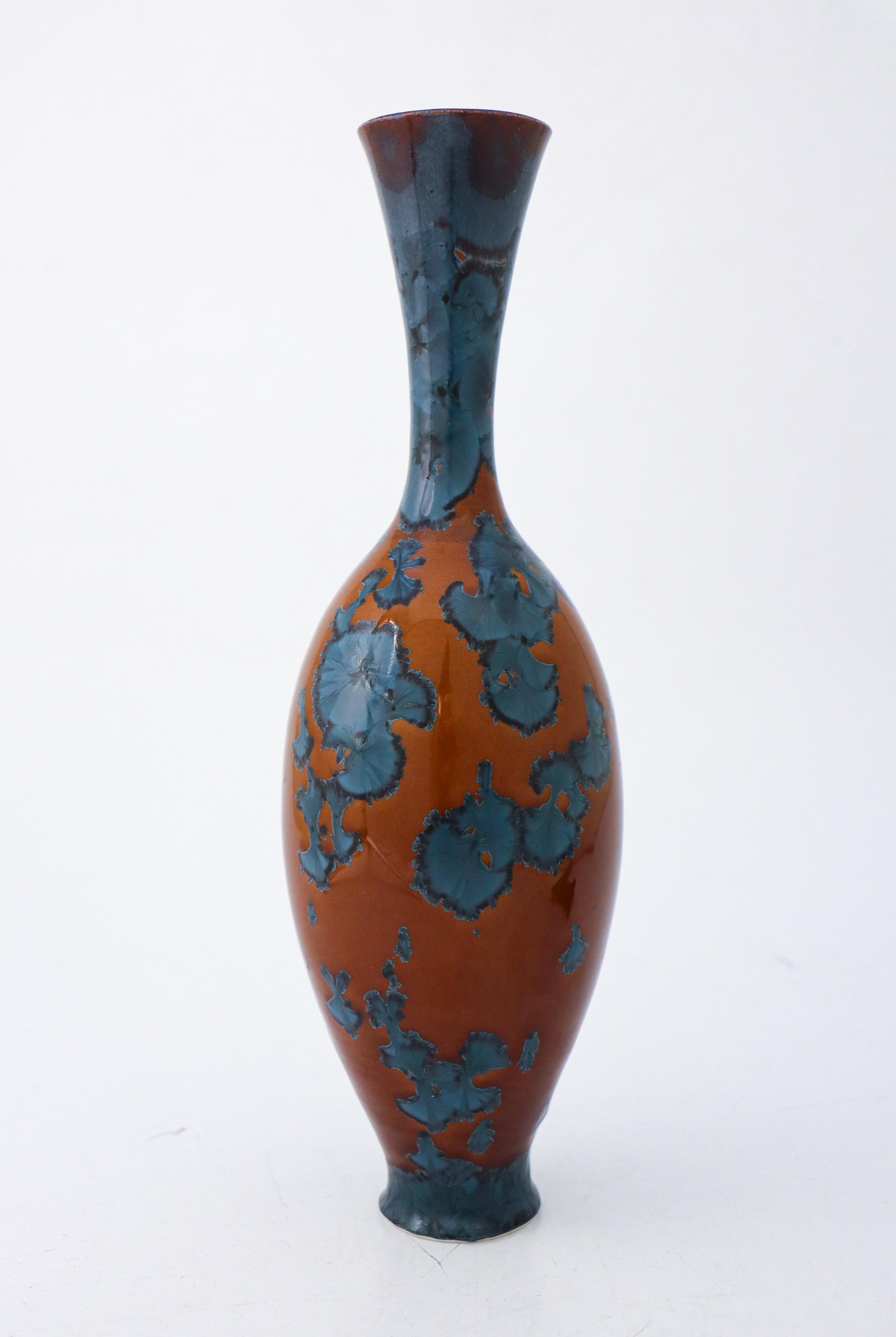 A unique vase in a brown color with a blue crystalline glaze created by the contemporary Swedish artist Isak Isaksson in his own studio. The vase is 31 cm (12.4