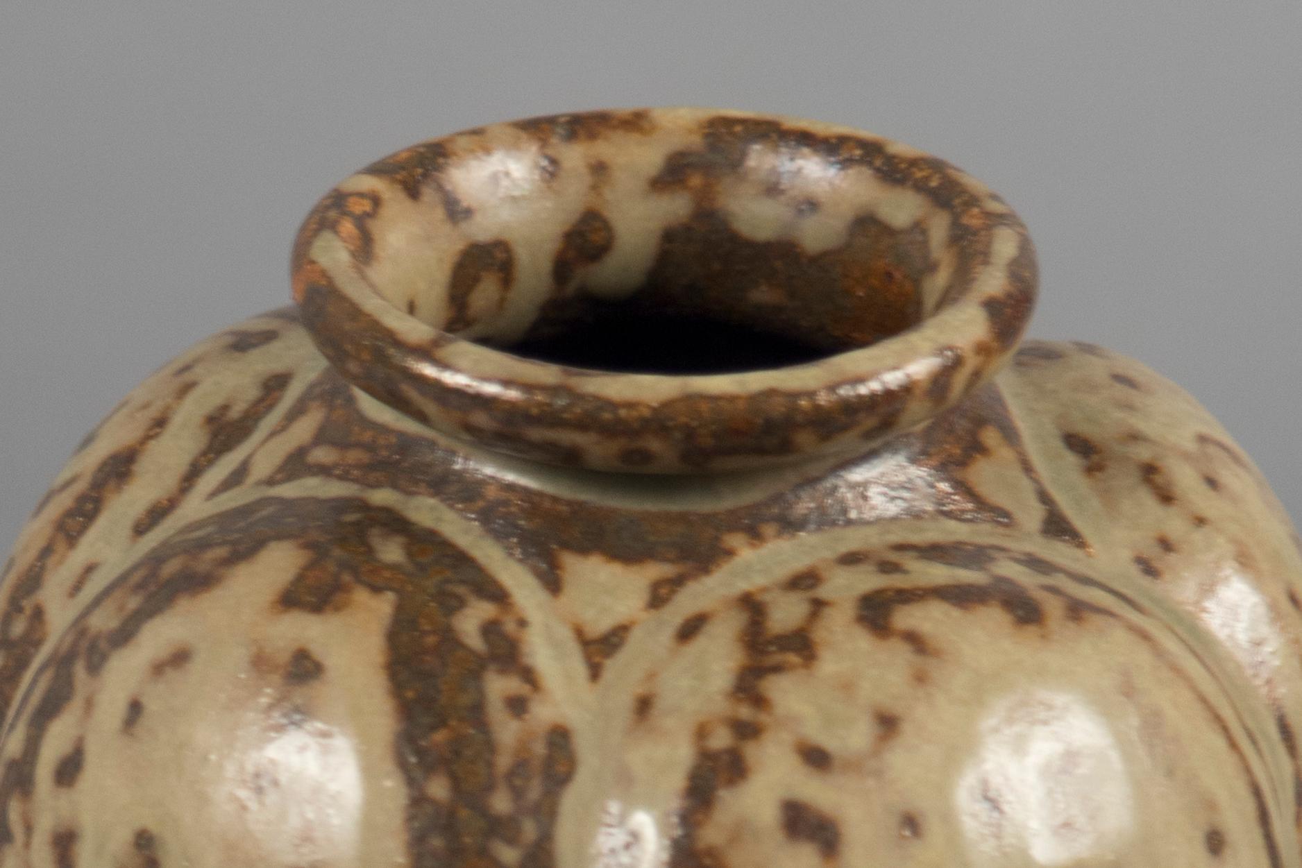 Stoneware vessel with lobed sides and a short, waisted neck.
 