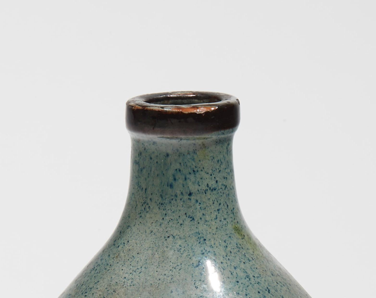 Vase ovoïde en faïence à col annulaire légèrement saillant, décor moderniste en émail de lignes noires et bleues interrompues par des carrés bleus sur la panse, fond bleu granité. Signé 
