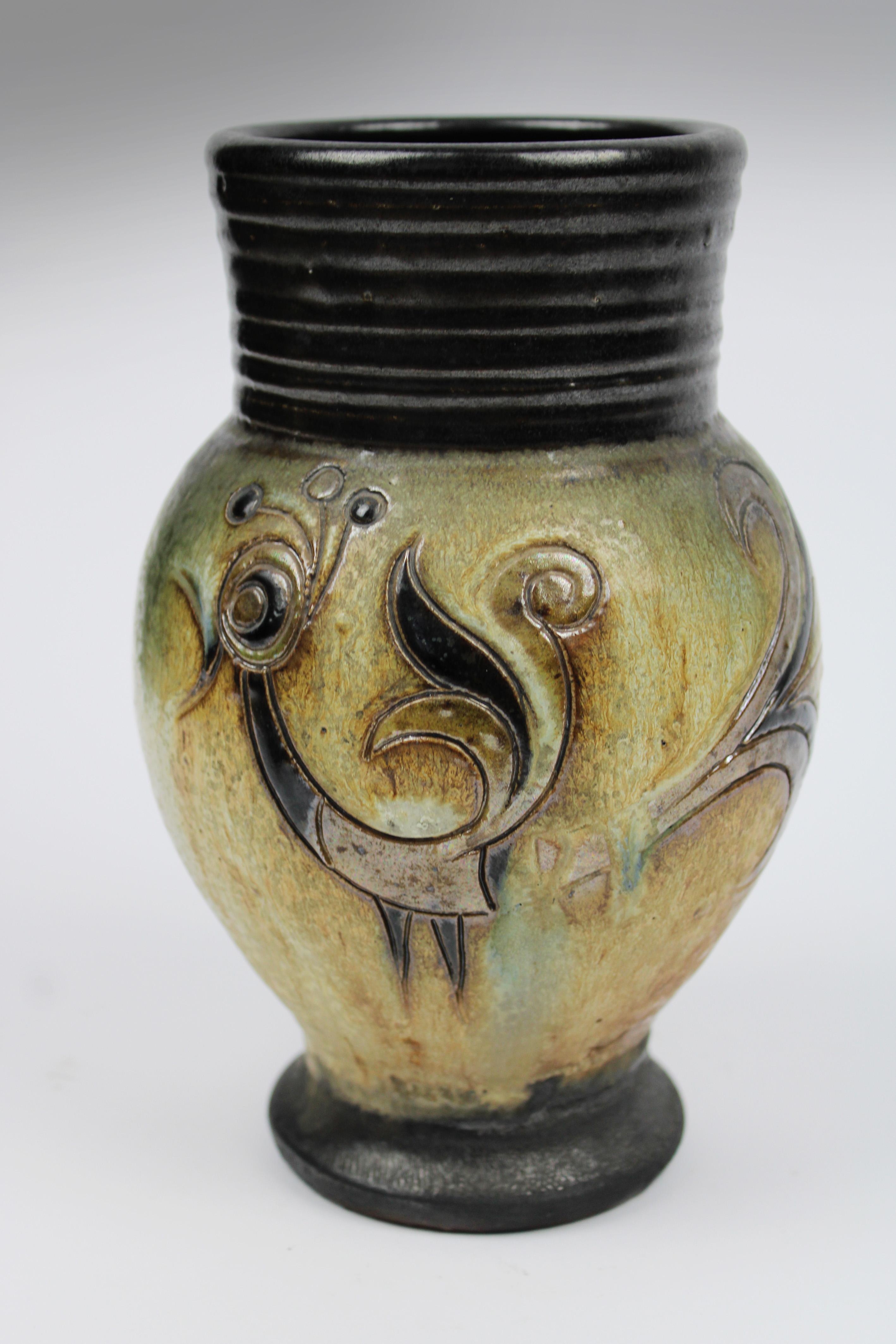 Nous vous présentons un vase en céramique exquis de l'artiste renommé Roger Guerin, un céramiste belge actif en France. Cette pièce est un exemple typique du design Art déco, avec des oiseaux faits à la main et des reliefs complexes qui soulignent