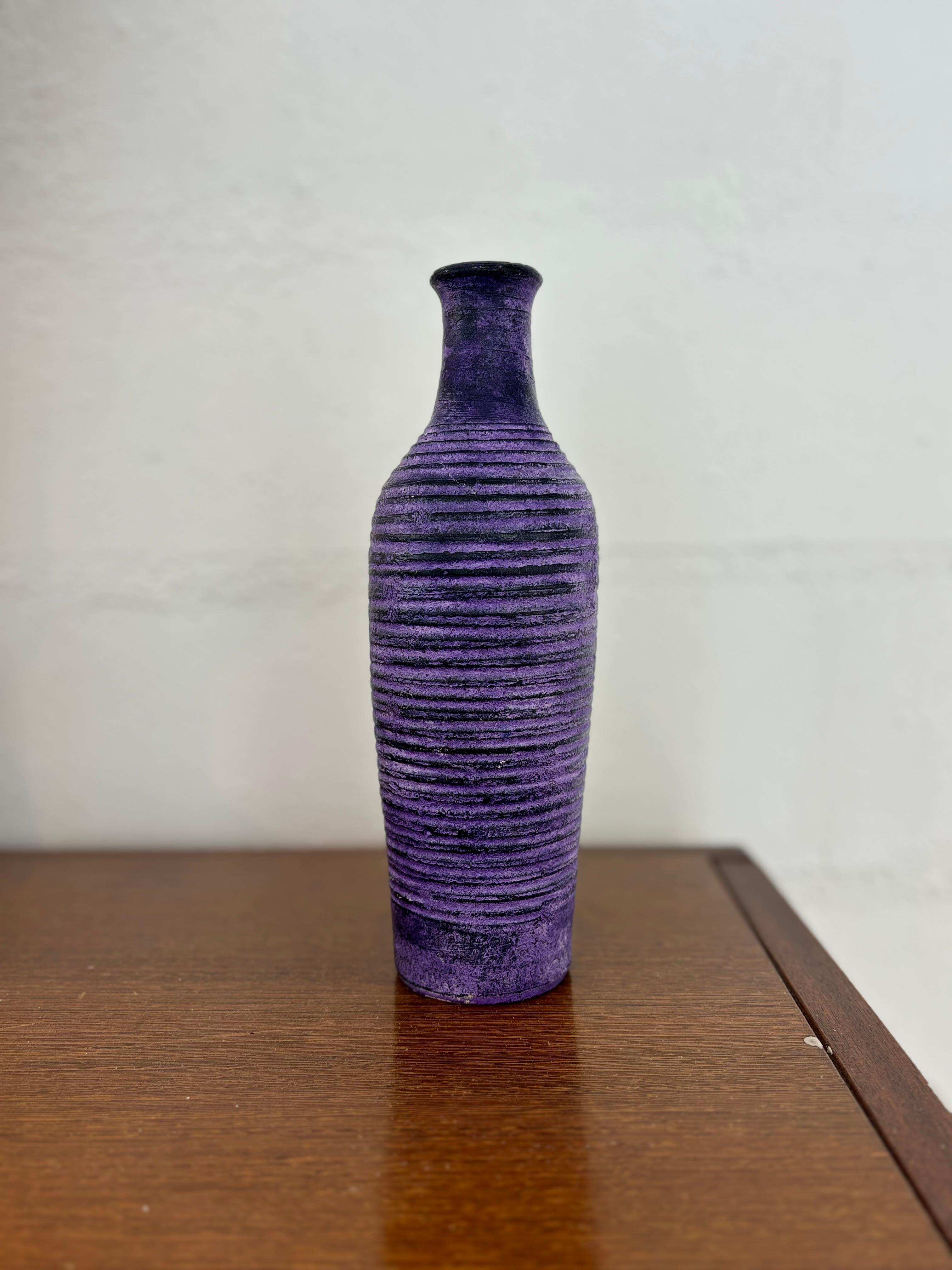Jolie vase bouteille par Mado Jolain à émaillage violet et décor circulaire courant sur la panse. 
Signé sous la base 