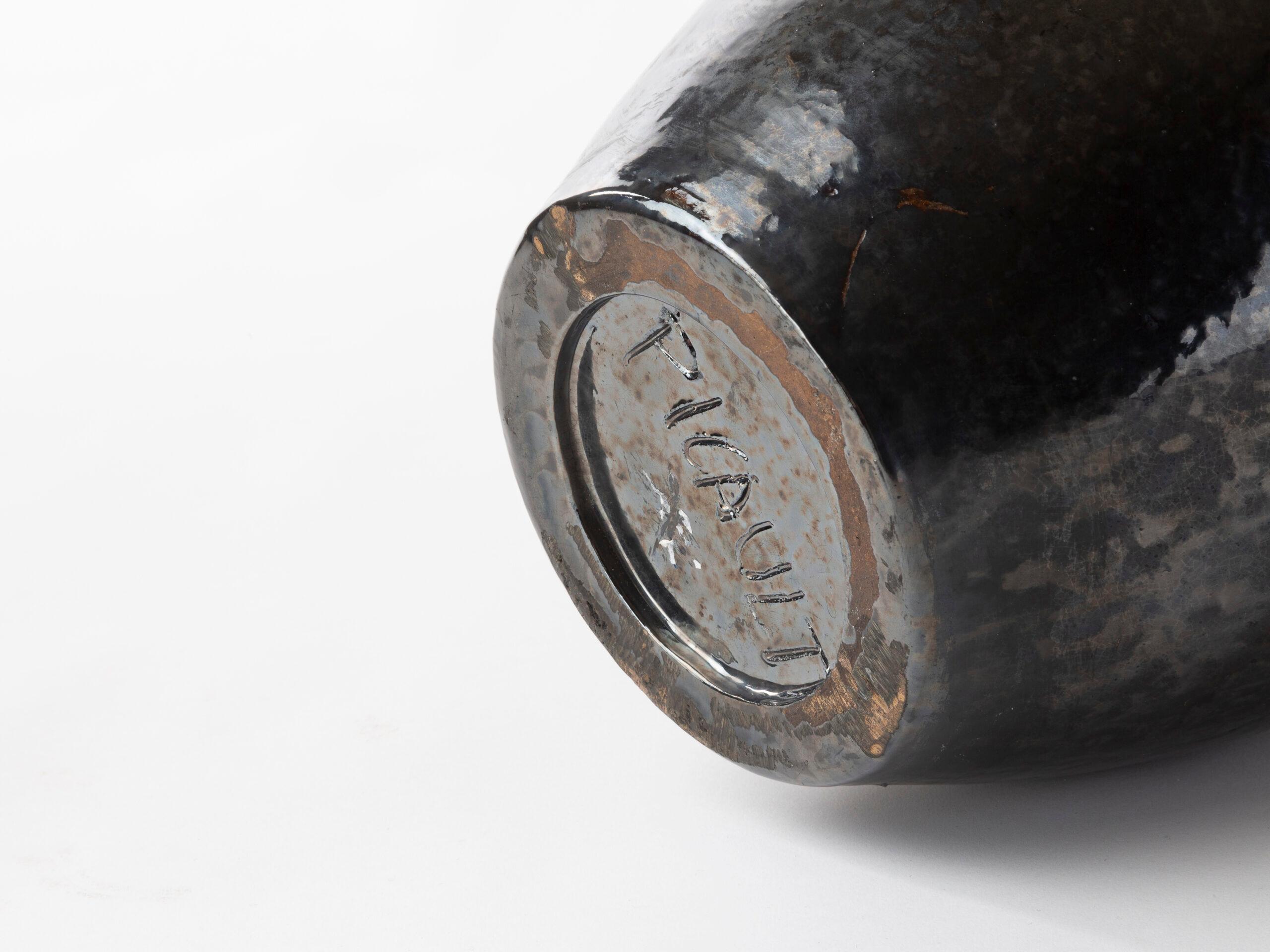 This elegant vase by Robert Picault showcases his mastery of ceramic artistry. Crafted in lustrous black-glazed earthenware, the piece features a softly rounded body that tapers into a narrow neck, creating a harmonious and timeless silhouette. The