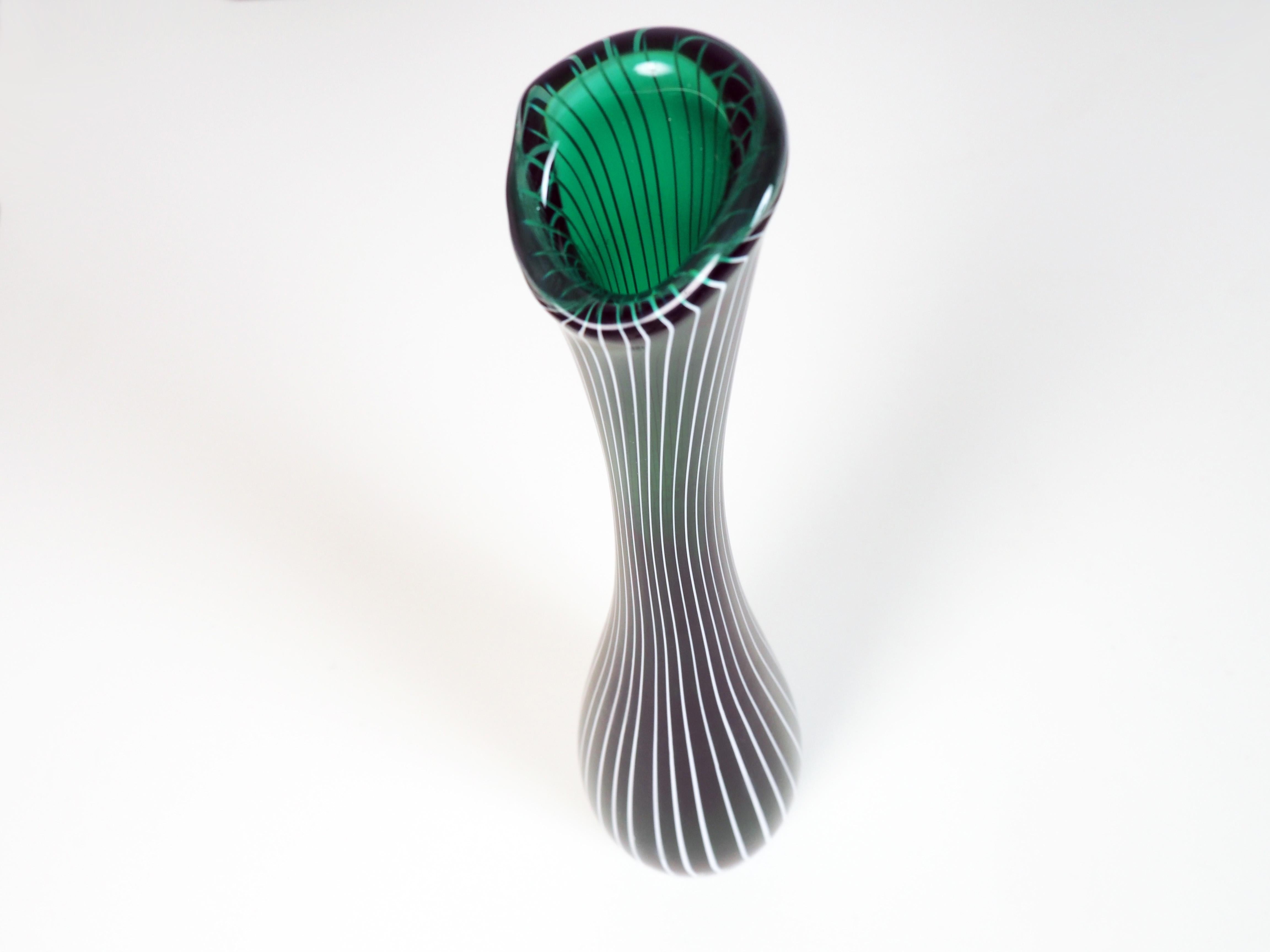 Tall glass vase by the Swedish glass artist Vicke Lindstrand for Kosta Glasbruk. The vase was designed in the 1950s when Vicke Lindstrand returned to his favourite material: handcrafted glass.
The vase is in party green, partly clear glass, with a
