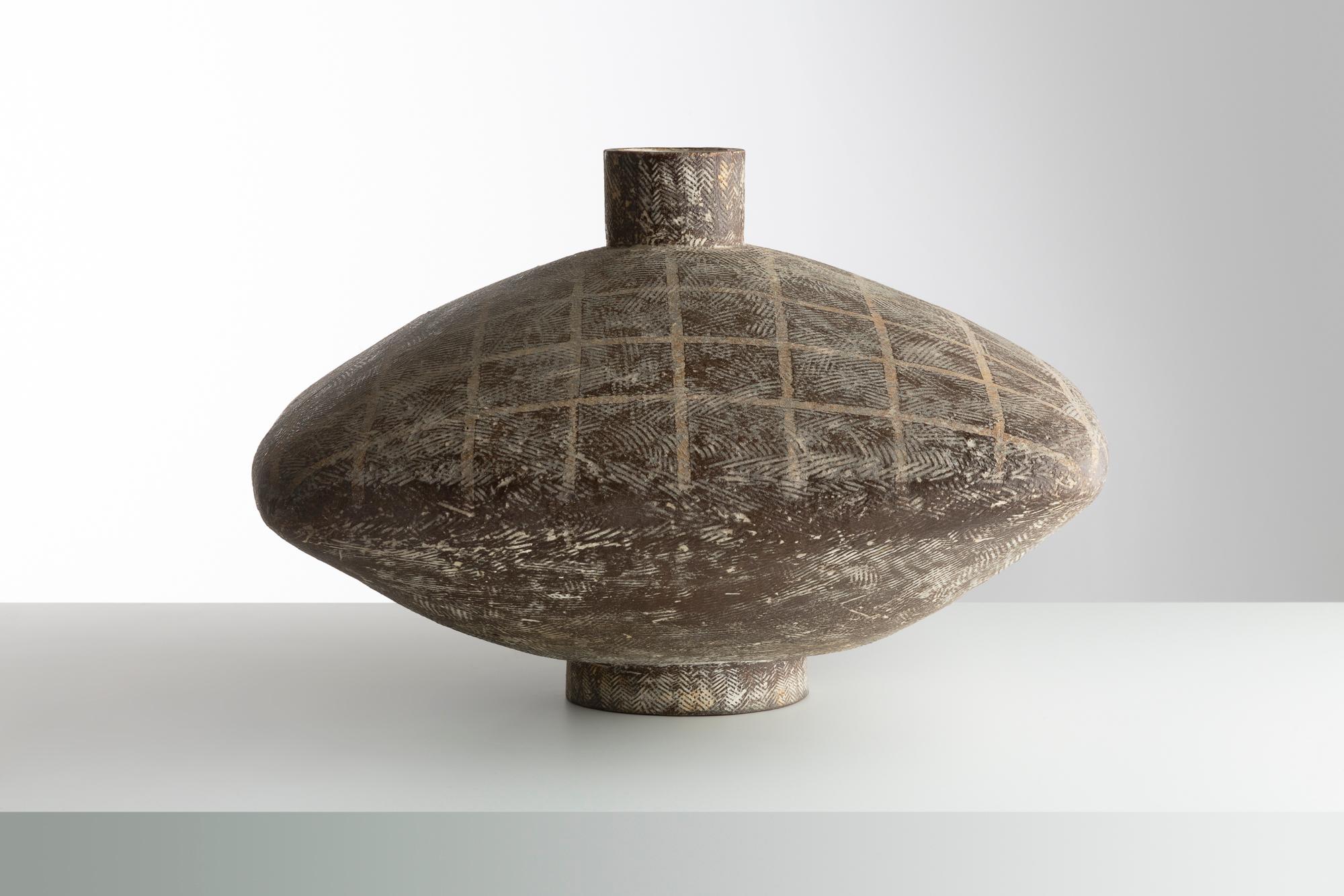 Diese monumentale Steingutvase von Claude Conover zeigt seine charakteristische handgefertigte Konstruktion und strukturierte Oberfläche. Mit seiner geometrischen, abgeflachten Form und den filigranen Ritzmustern spiegelt das Stück Conovers