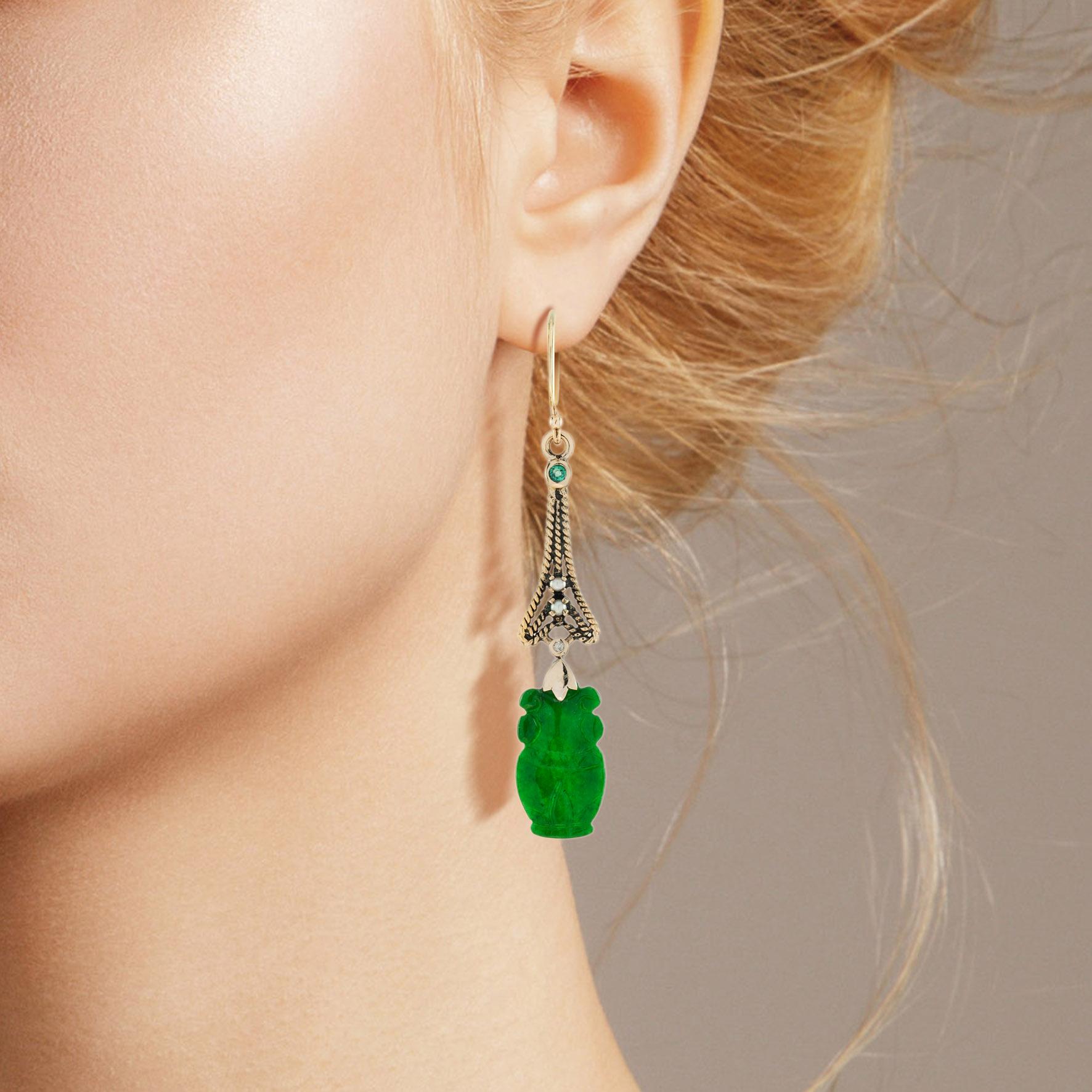 The natural jade in these lovely earrings has some very special shape. Both pieces have a strong green color and well vase carvings. The jade is suspended in a 9k yellow gold setting with pearl, diamond, and emerald geometric link on the top. The