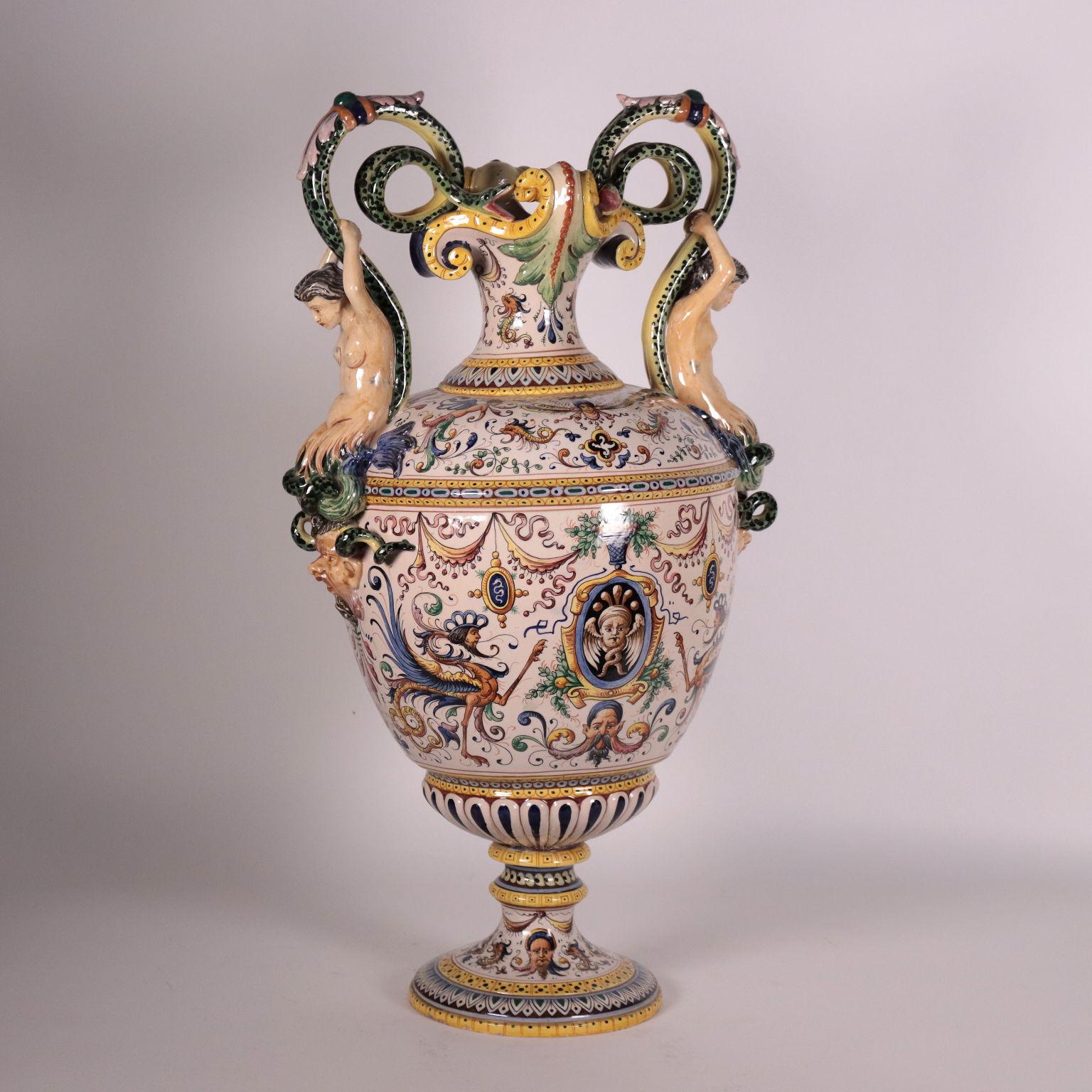 Sixteenth-century style majolica ceramica base with rich grotesque decoration; in the reserves, the bust of a young man and an allegorical figure. The handles are impressive, with snakes, mermaids and masks.