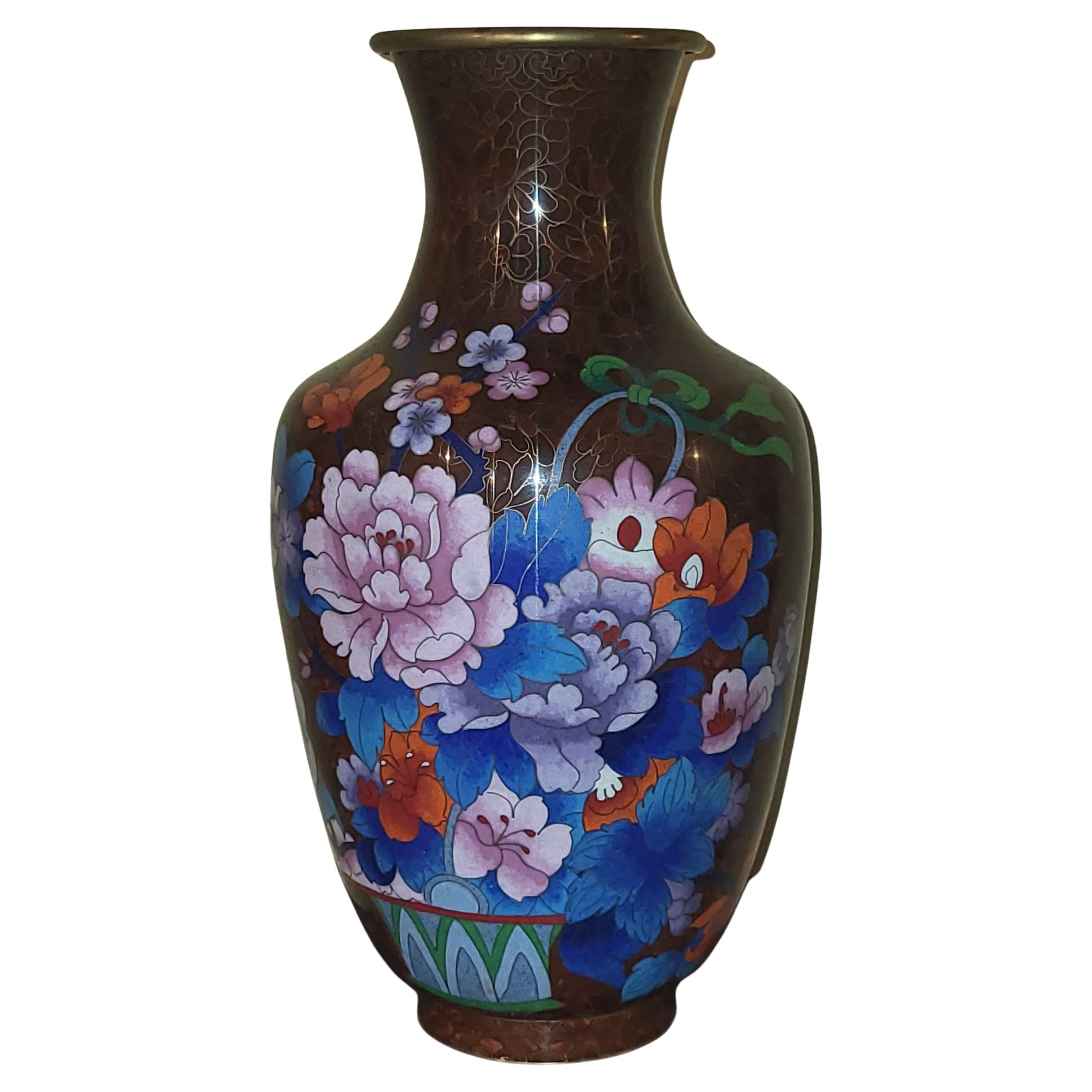 Grand vase des années 1950/60 provenant de Chine, en émaux cloisonnés sur cuivre avec un beau décor de fleurs.
Le cerclage au col est en laiton doré , permet un beau contraste avec le fond brun chocolat du vase ainsi les couleurs florales sont mises