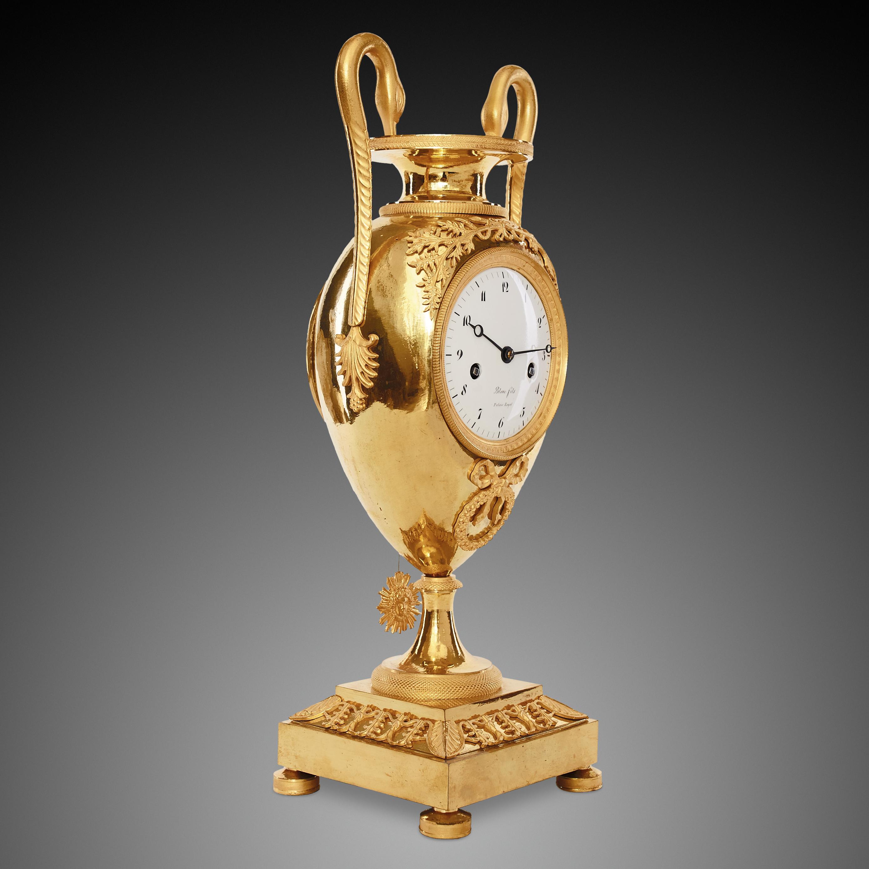 This finely chiseled vase clock was cast from bronze with gilded elements originated from the first half of the nineteenth century. The Empire style was based on elements of the Roman Empire and its culture, which had been rediscovered starting in