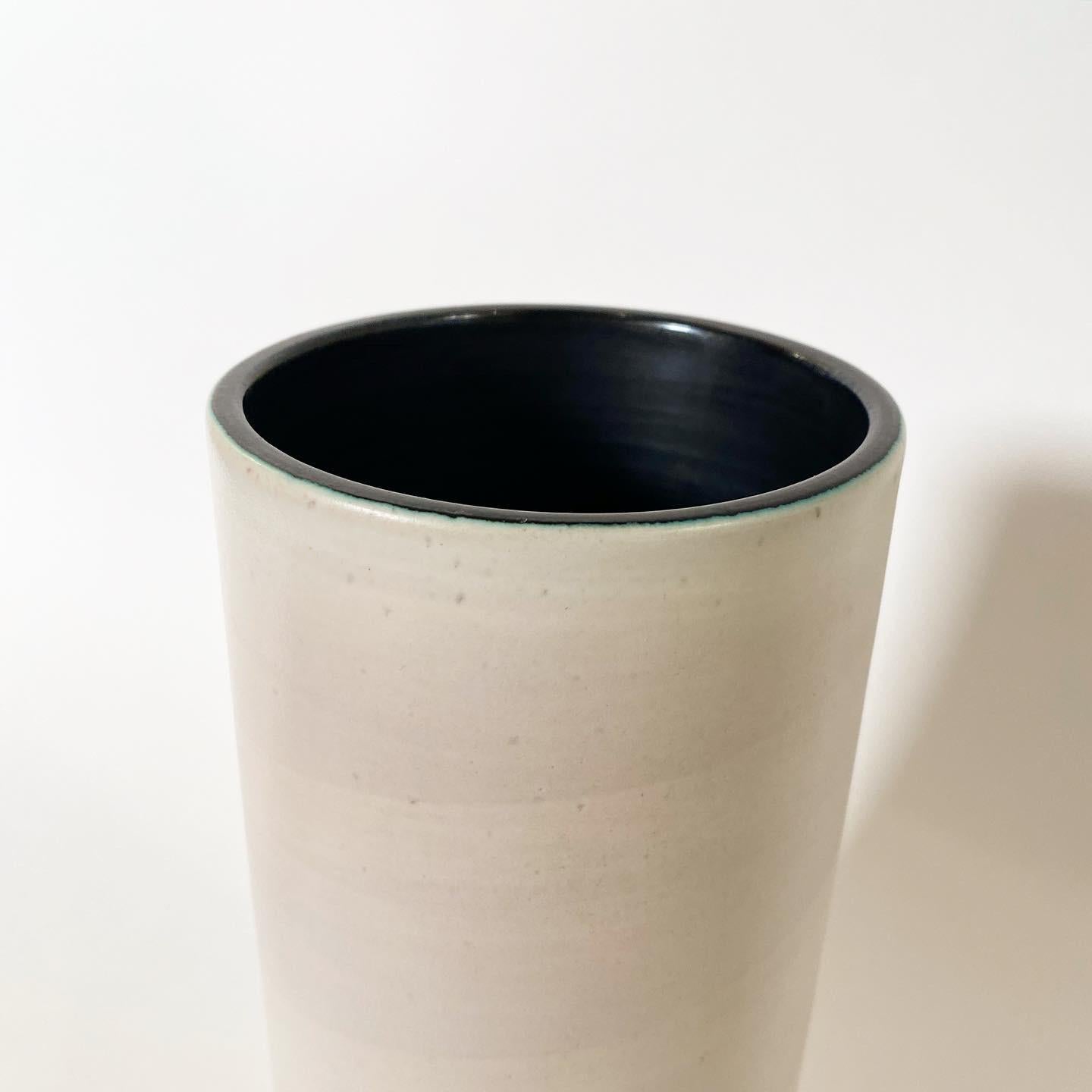 Vase Cylindre en céramique émaillée blanc enrubanné, intérieur noir, circa 1955.
Signé 