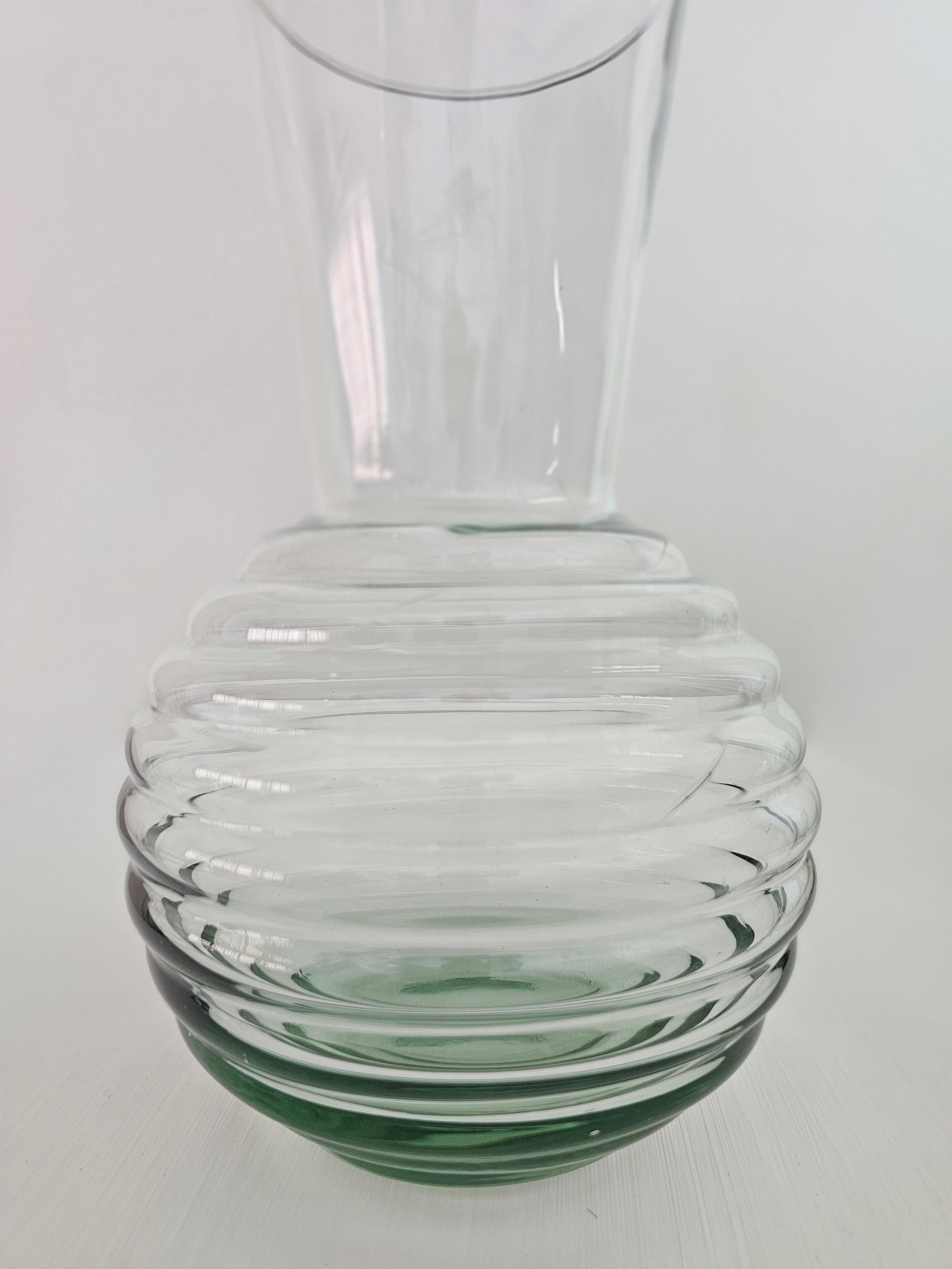 Elegant vase en verre transparent. Corps sphérique avec col en trompette, bouche circulaire. Base circulaire nervurée dans les tons de vert. Veuillez regarder attentivement la vidéo et les photos, merci.

Poids : 0,990 kg
Diamètre de la bouche :