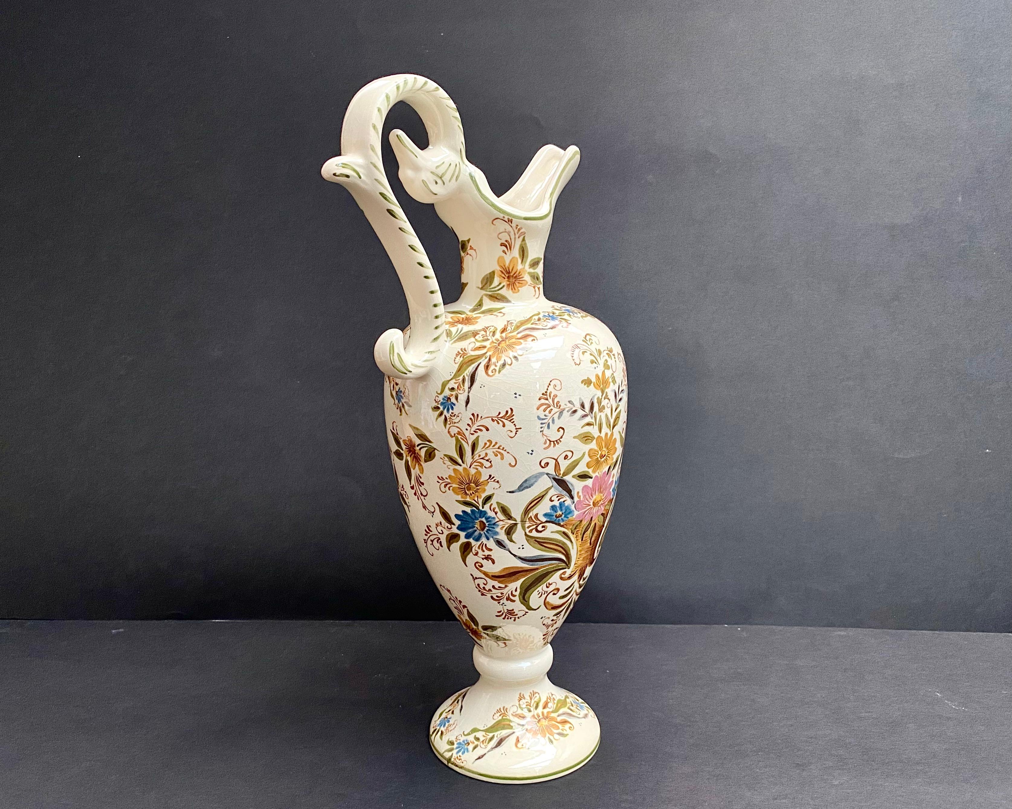Enamelled faience ewer from the 1950s, made in Belgium, attributed to Hubert Bequet & Holland Delft’s.

Vintage vase with a beautifull ivory background decorated with a bright colorful pattern of a colorful flowers.

Marking on the bottom: Holland