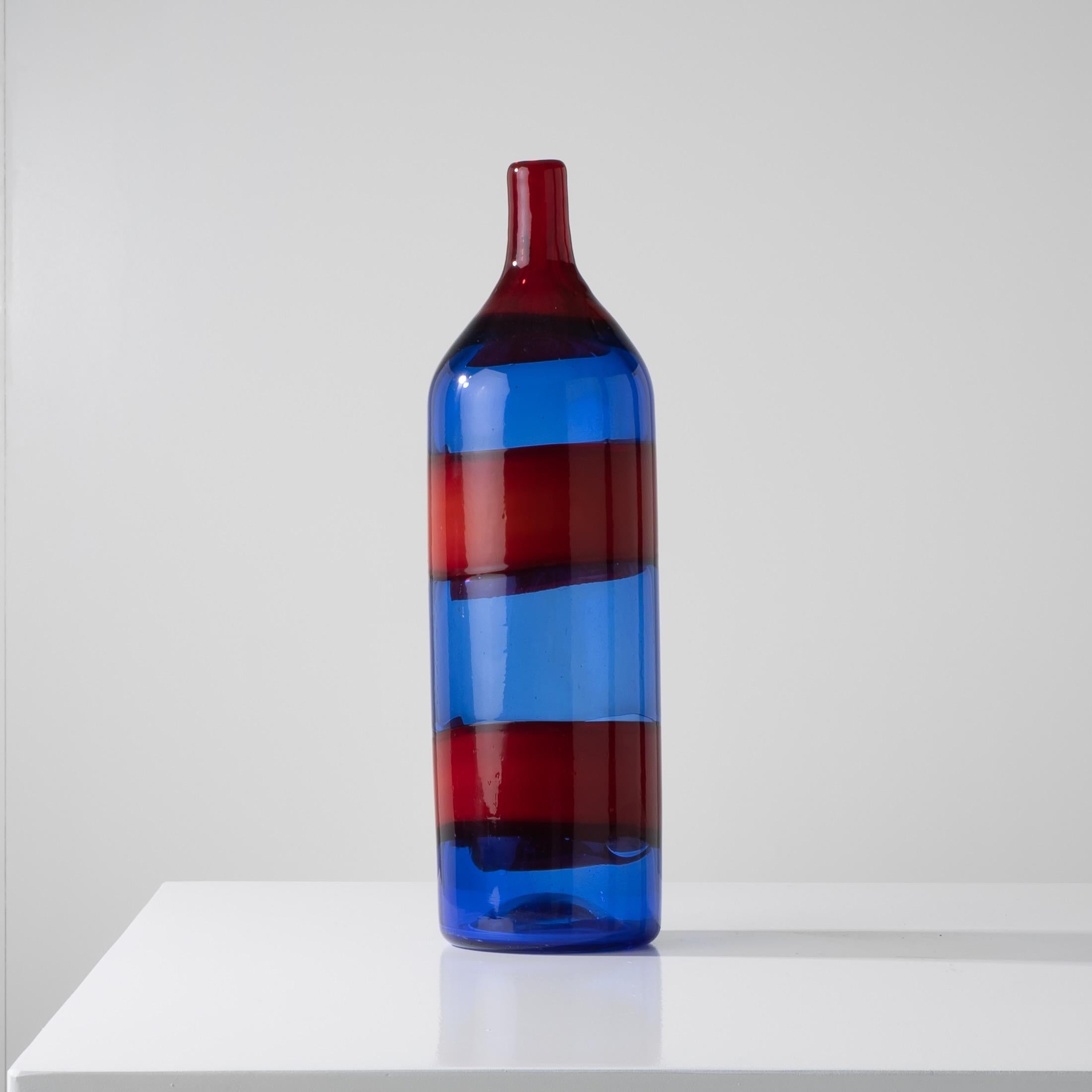Large blue blown glass bottle vase decorated with two hot applied red bands.
The neck consists of a layer of translucent red glass which is itself different from the glass used for the bands on the body of the vase which have a white