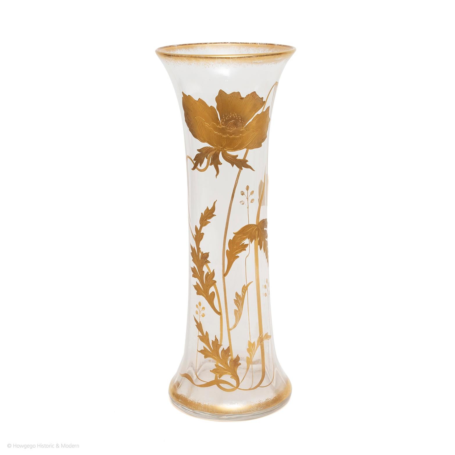 Grand vase en verre côtelé en cristal St Louis, décoré d'une fleur de Convolvulus émaillée à l'or fin. Le sommet est orné de fines plumes dorées. La base du vase est ornée d'un anneau doré et un grand convolvulus stylisé et doré en profond relief
