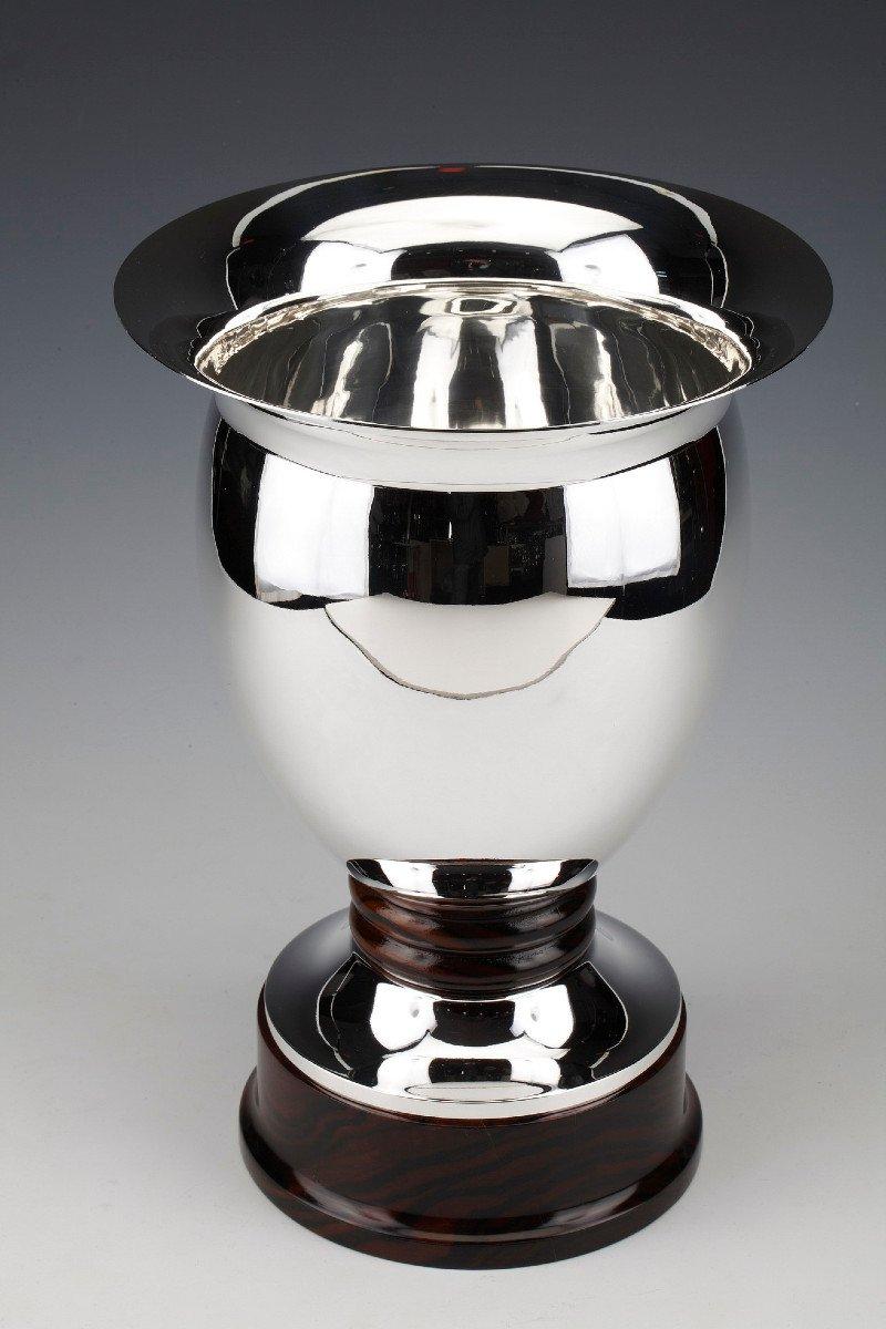 An ovoid-shaped vase in solid silver, mounted on a rosewood base, surrounded by two rosewood rings, the plain body ends with a flat flared neck. Dimensions: Height 34 cm Base diameter 17 cm Neck diameter 24 cm Material: Silver (900 °°) Gross weight:
