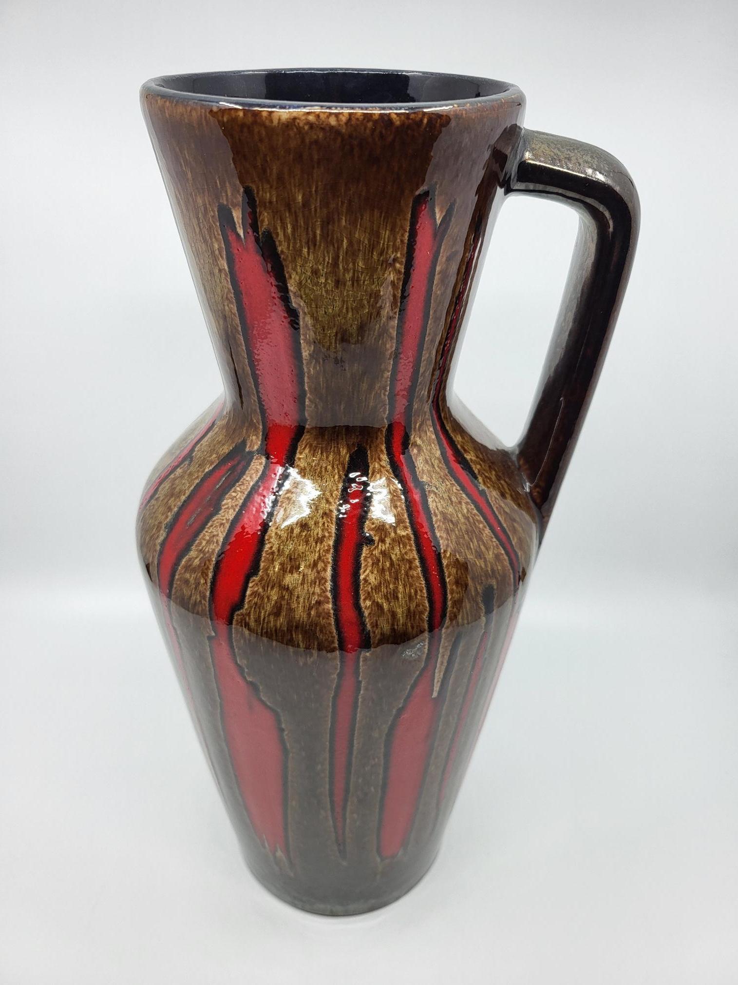 Grande vaso Scheurich ansé, con una colorazione di base  marron agrémenté de liseret rouge flamboyant, très représentatif des productions Allemandes des années 1960.
Une très bel hauteur
Il design atipico di Ces  Le produzioni appassionano un gran
